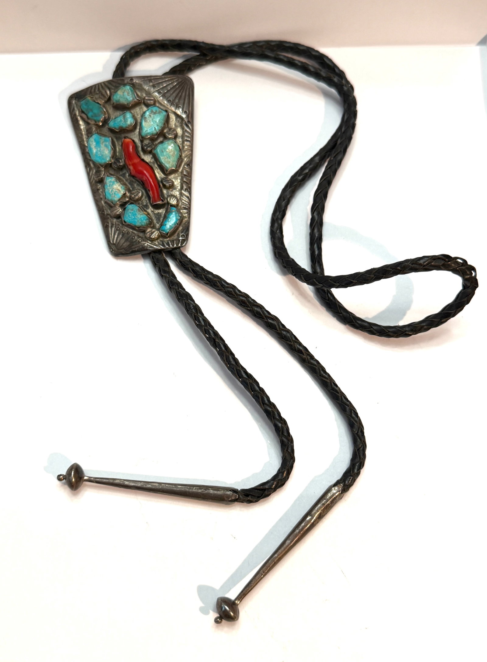 Native American Style Turquoise & Coral Bolo Tie ? Bennett Pat. Pend. Clasp: Vintage Southwestern / Native American style bolo tie featuring a large trapezoid-shaped silver-tone slide set with rough-cut turquoise stones and a central red coral accent. Decorative hand-tooled fa