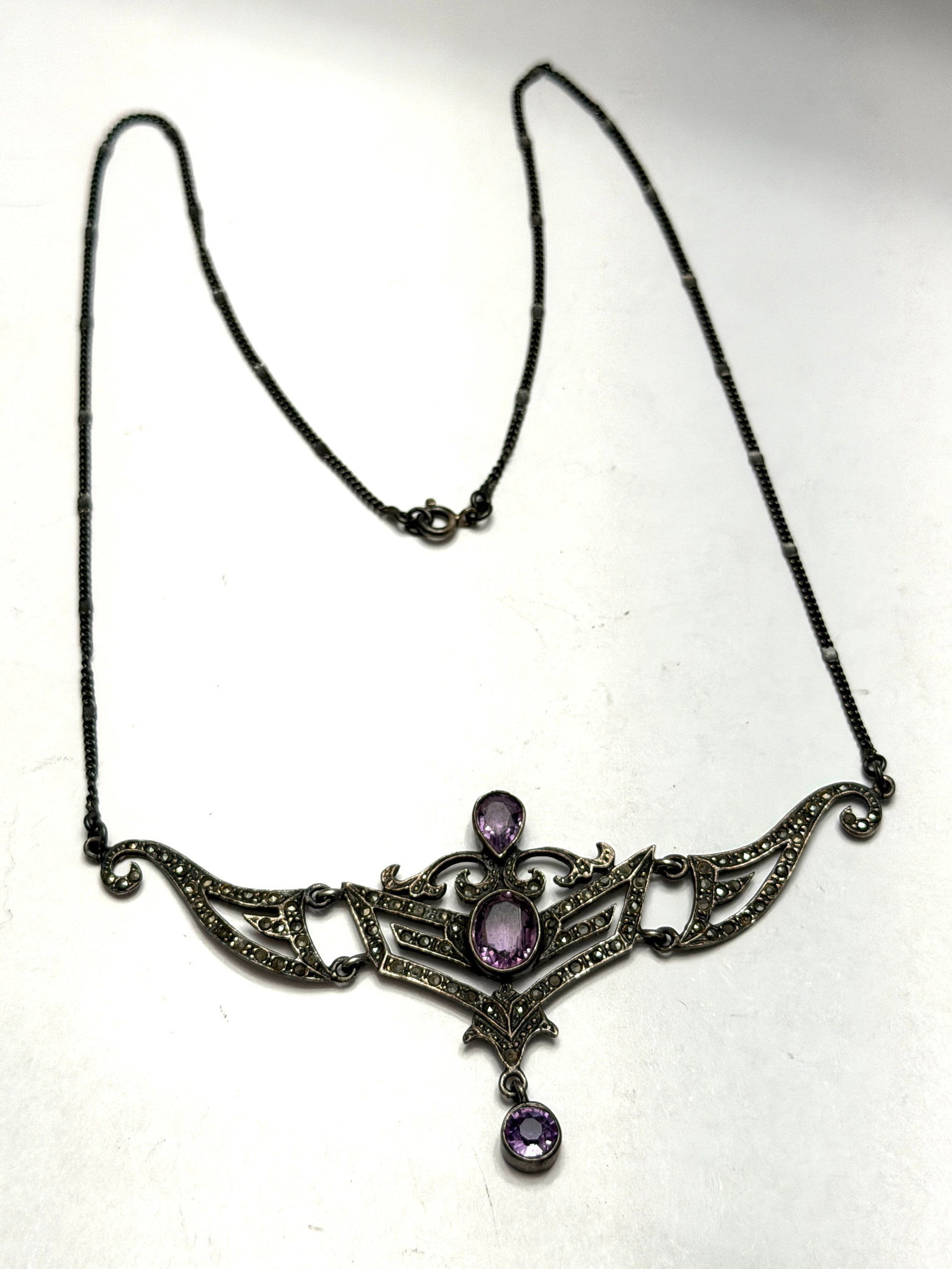 Antique Art Deco Sterling Silver Amethyst & Marcasite Necklace: An exquisite antique Art Deco sterling silver necklace featuring luminous faceted amethyst gemstones accented by sparkling marcasite detailing in a beautifully symmetrical geometric design. This elega