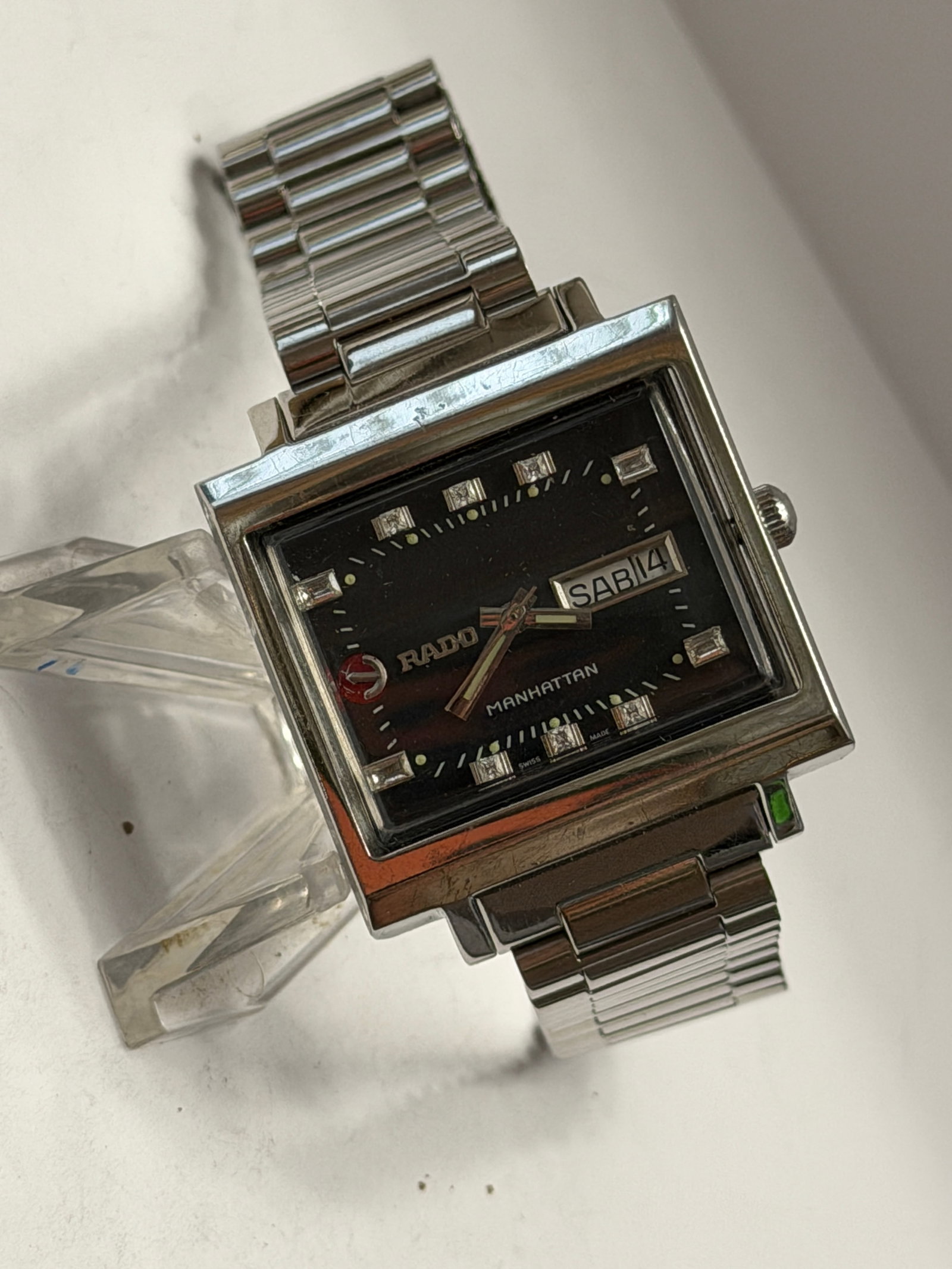 Rado Manhattan Day-Date Rectangular Men?s Watch Stainless Steel: Vintage Rado Manhattan wristwatch featuring a bold rectangular stainless steel case with a striking black dial and integrated stretch bracelet. This classic retro-inspired timepiece includes a day-dat