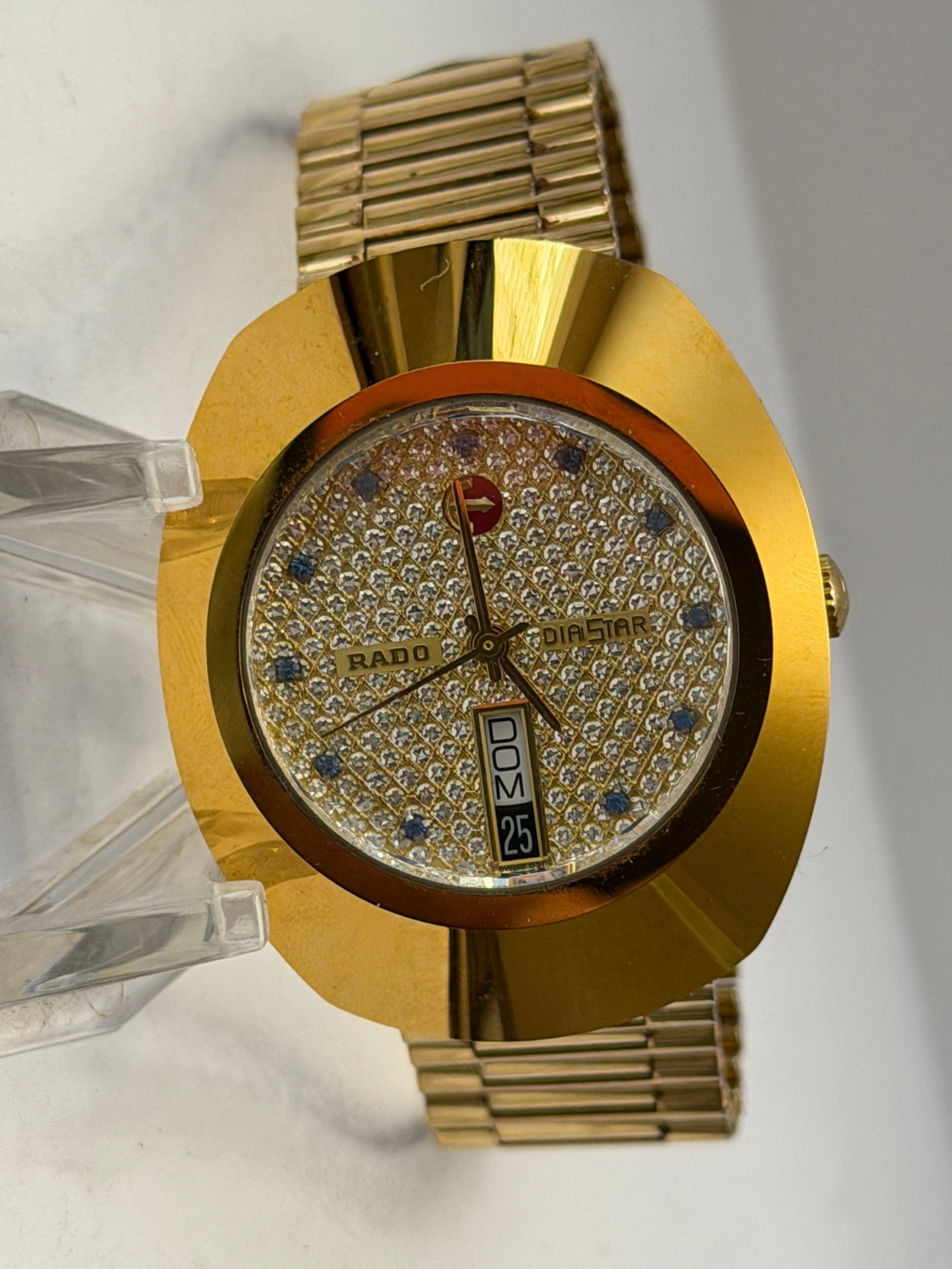 Vintage Rado DiaStar Gold Tone Day-Date Wristwatch: Vintage Rado DiaStar wristwatch featuring a striking gold-tone oval case with integrated bracelet and textured crystal-style dial. Dial is accented with blue hour markers, gold-tone hands, and the ico