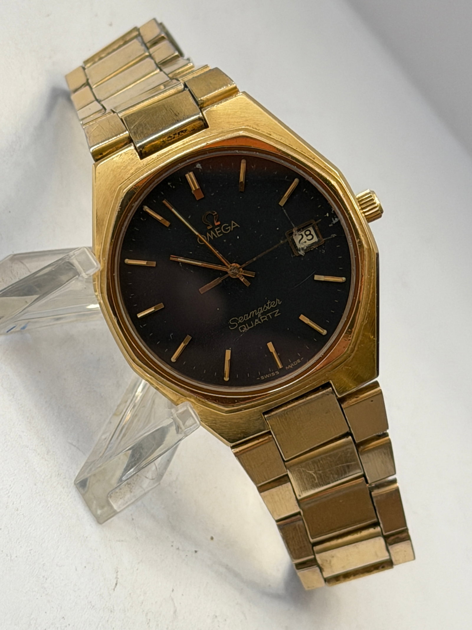 Omega Seamaster Quartz Gold-Tone Wristwatch ? Black Dial Date Watch: Elegant vintage Omega Seamaster Quartz wristwatch featuring a striking black dial housed in a gold-tone octagonal case with integrated bracelet. This classic Swiss-made Omega combines refined minimali