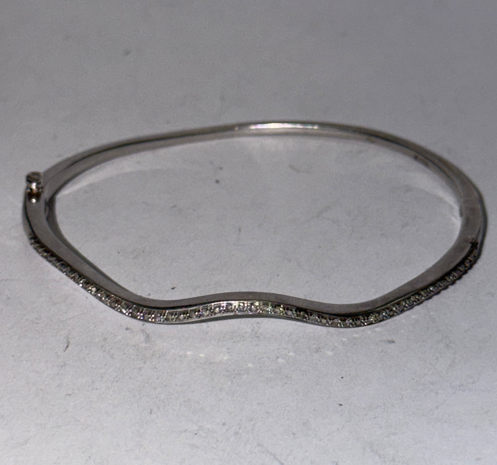 Diamond Accent Hinged Bangle Bracelet ? White Metal Wave Design Bracelet: Elegant vintage hinged bangle bracelet featuring a sleek wave-form design accented with a row of small sparkling stones, likely diamonds or diamond simulants. The bracelet has a clean modernist look w