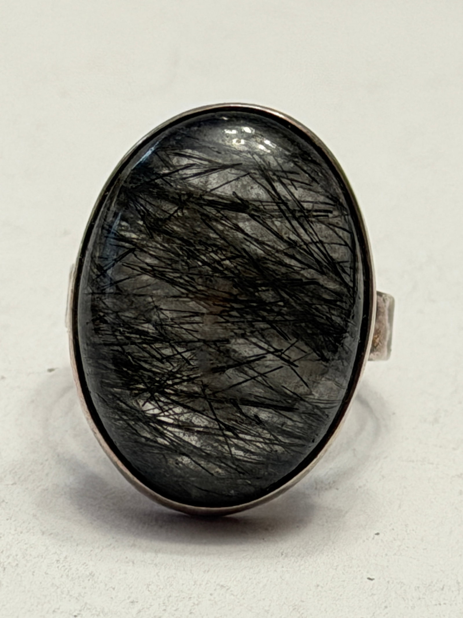 Modernist Sterling Silver Black Rutilated Quartz Ring Size 9: Striking modernist sterling silver ring featuring a large oval black rutilated quartz cabochon with dramatic needle-like inclusions throughout the stone. The ring has a bold handcrafted artisan style 