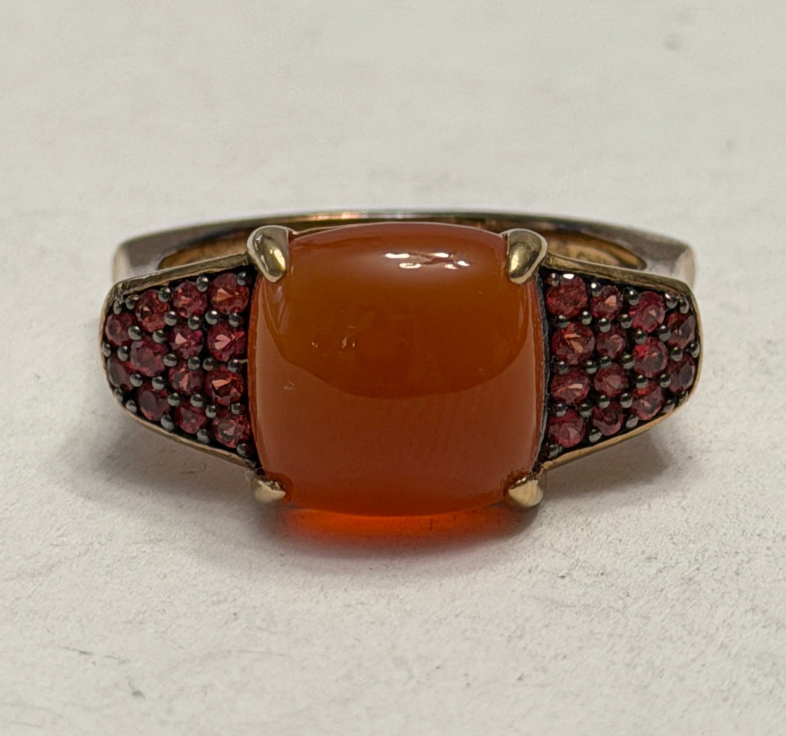 Sterling Silver Carnelian and Red Gemstone Statement Ring Size 11: Elegant sterling silver statement ring featuring a large cushion-cut orange carnelian cabochon accented by pavé-set deep red gemstones on each shoulder, likely garnets or red cubic zirconia. The 