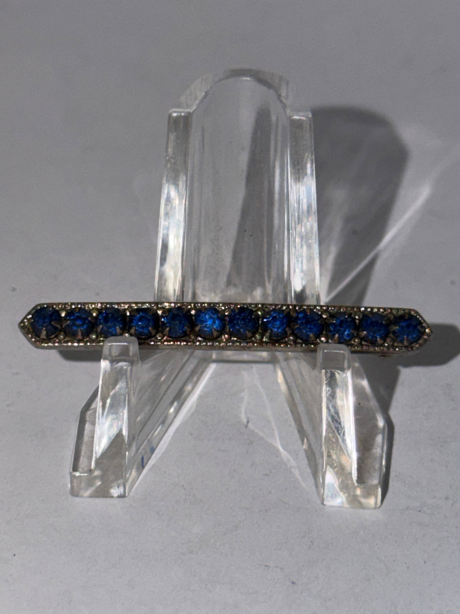 Art Deco Blue Rhinestone Bar Brooch Pin Silver Tone Costume Jewelry: Art Deco style bar brooch featuring a striking row of deep cobalt blue rhinestones set in a silver tone metal frame with pointed geometric ends and classic linear styling. This elegant antique-inspire