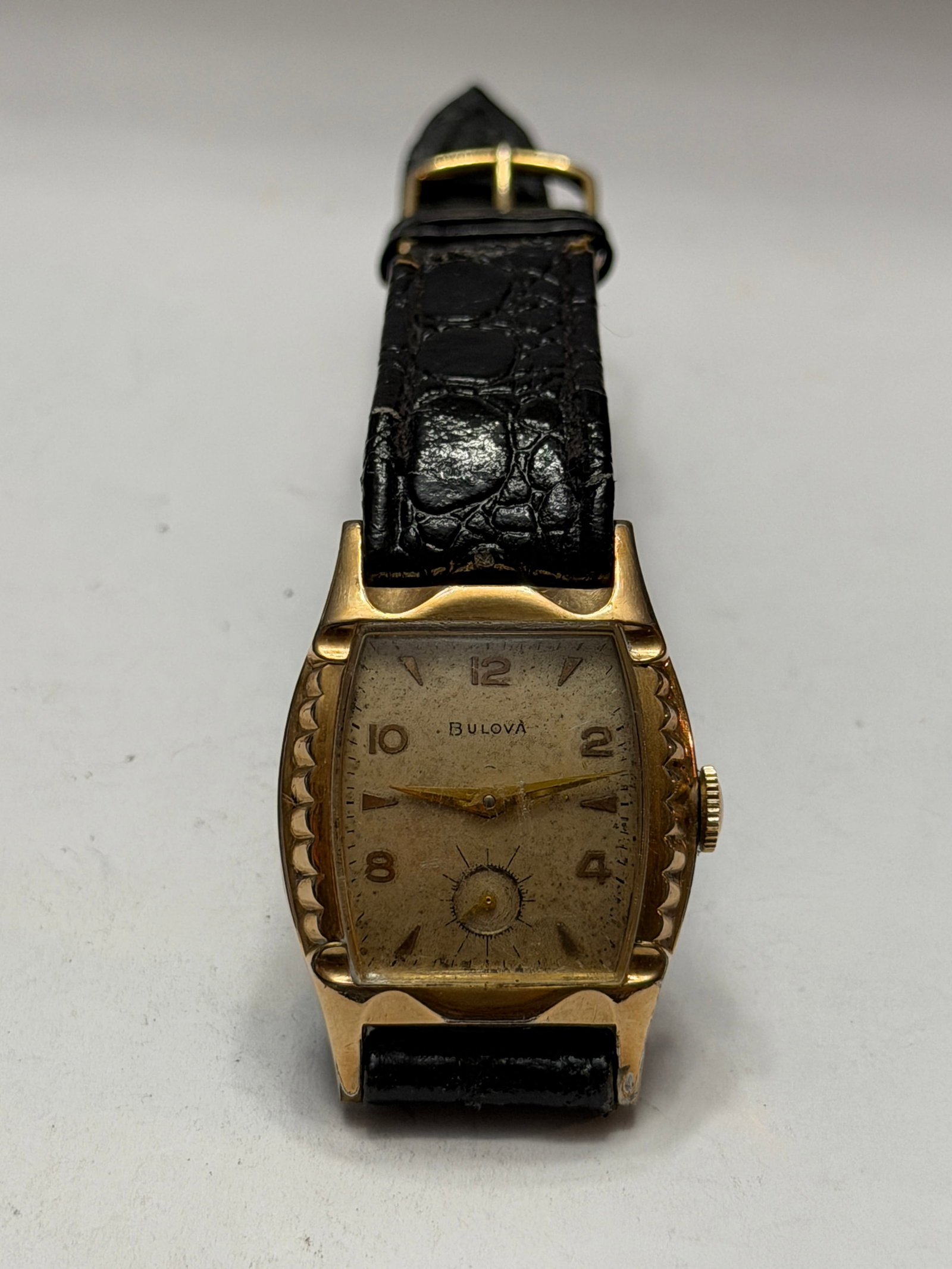 Vintage Bulova Curvex-Style Manual Wind Wristwatch ? Art Deco Case: Elegant vintage Bulova wristwatch featuring a classic curved rectangular (tonneau-style) case with strong Art Deco styling. The gold-tone case showcases decorative scalloped side detailing and a warm 