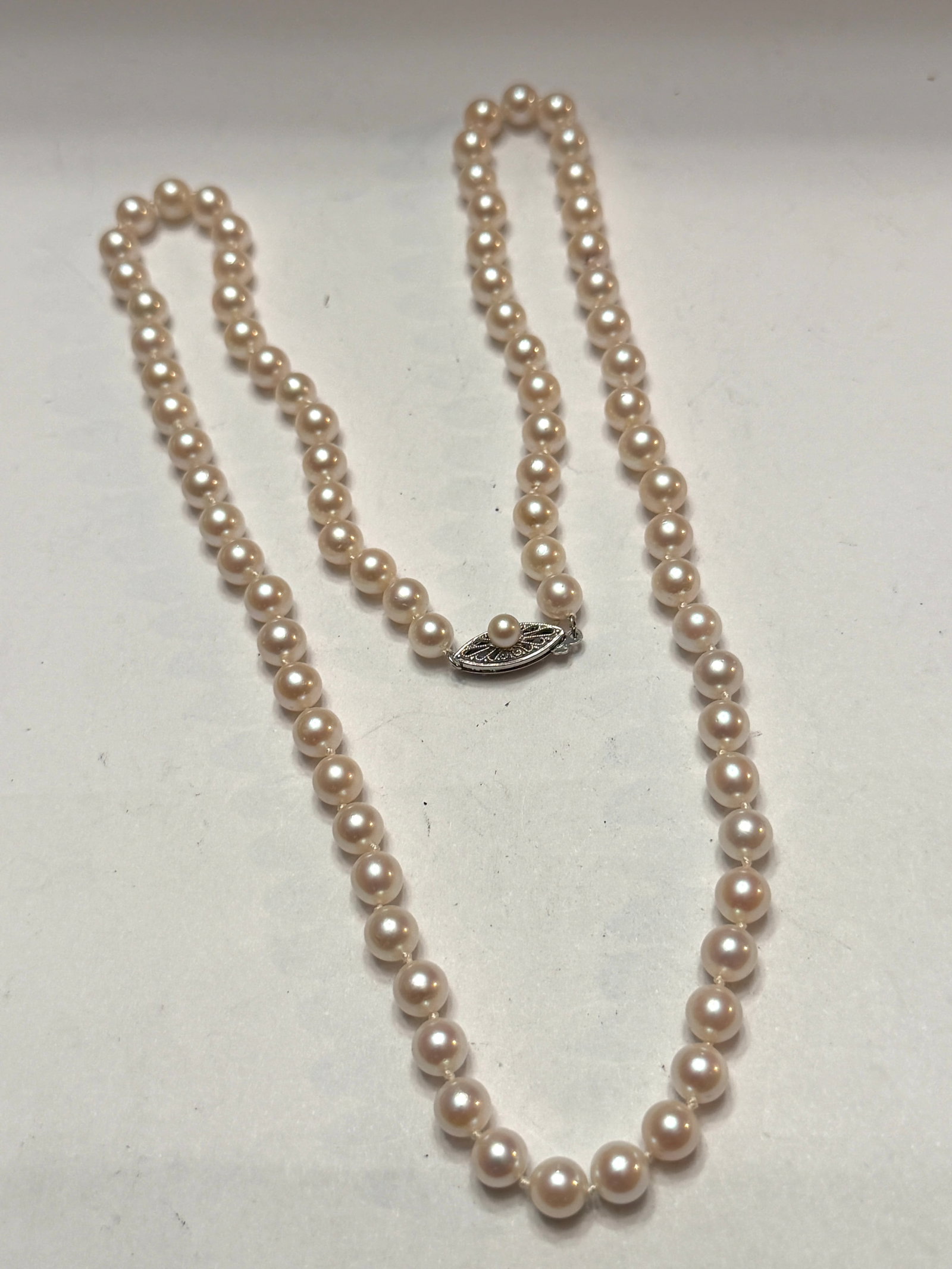 Vintage Cultured Pearl Necklace 14K White Gold Clasp Knotted Strand Estate Jewelry: Elegant vintage cultured pearl necklace featuring luminous creamy white pearls with beautiful soft iridescent luster throughout the strand and finished with an ornate 14K white gold filigree clasp mar