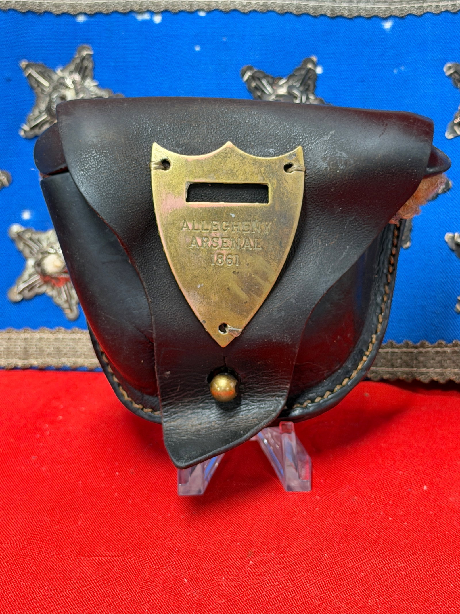Allegheny Arsenal 1861 Marked Leather Cartridge Box Pouch Civil War Style Collectible: Offered here is a black leather cartridge box or ammunition pouch featuring a brass-colored shield-shaped plate marked “ALLEGHENY ARSENAL 1861” on the front flap. The pouch includes a leather 