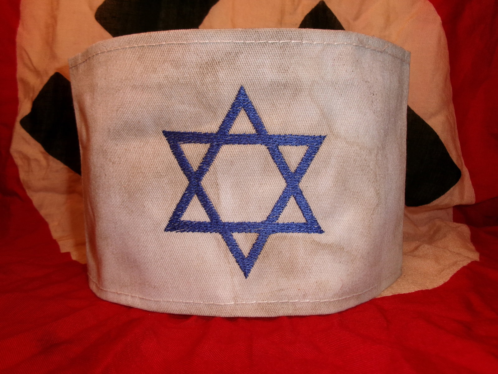 WWII Jewish Identification Armband with Star of David: This white cloth armband bears a blue embroidered Star of David, the identifying symbol imposed upon Jewish populations under Nazi rule during WWII. Armbands and identifying insignia of this type were