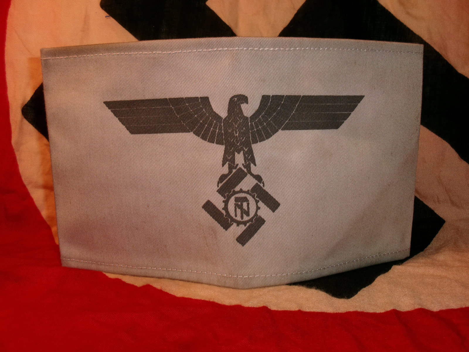 WWII German TeNo (Technische Nothilfe) Armband with RZM Paper Tag – Light Blue Variant: Offered here is a German TeNo (Technische Nothilfe) armband featuring the black TeNo eagle and cogwheel emblem on a light blue cloth band. The piece retains an RZM-style paper tag sewn into the seam a
