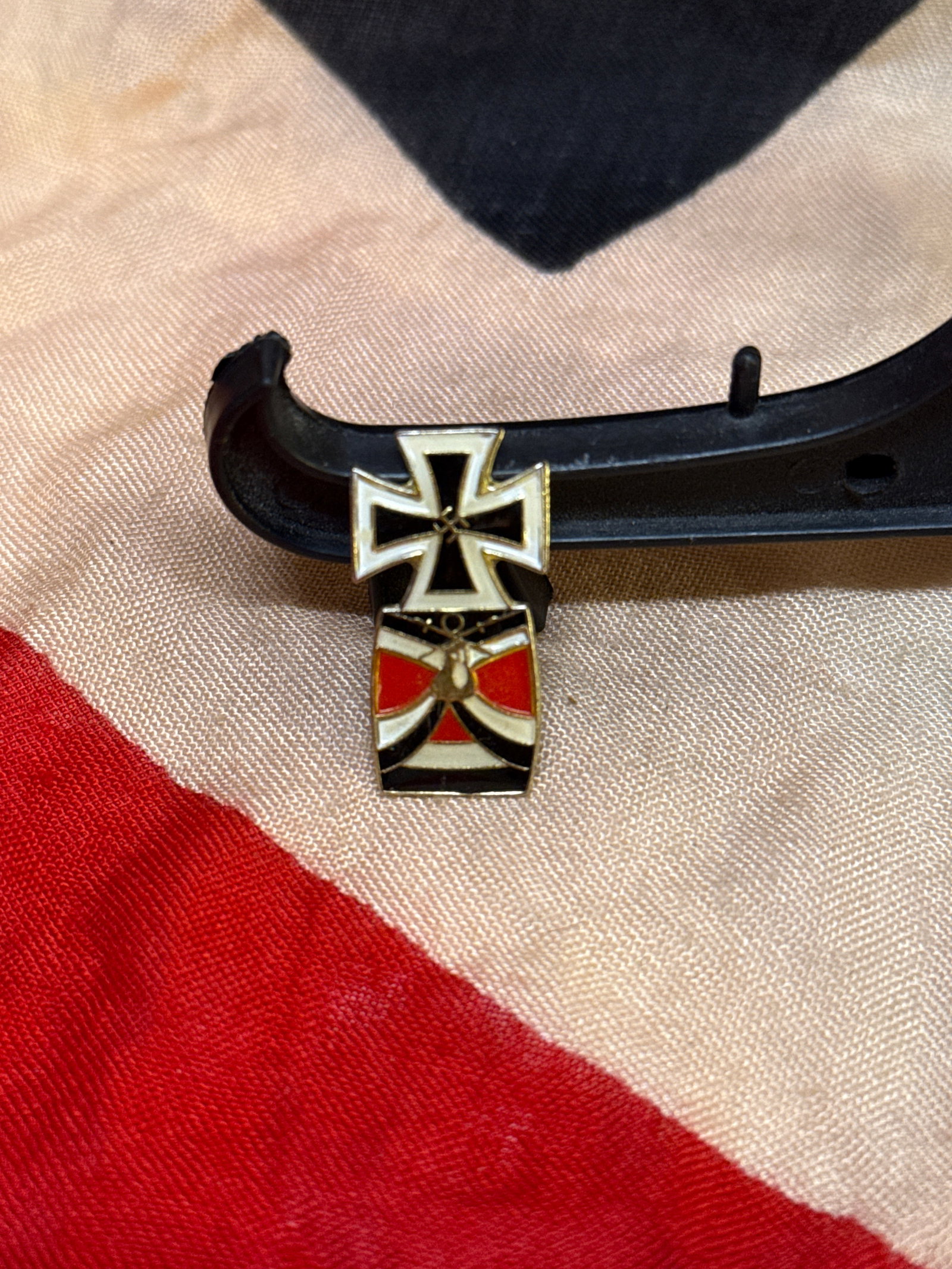Postwar 1957 Pattern German Iron Cross Veteran’s Lapel Pin: Small postwar German veteran’s lapel pin featuring a 1957-pattern Iron Cross above a stylized red, white, and black ribbon motif with central eagle device. Produced in enameled metal with screw-back
