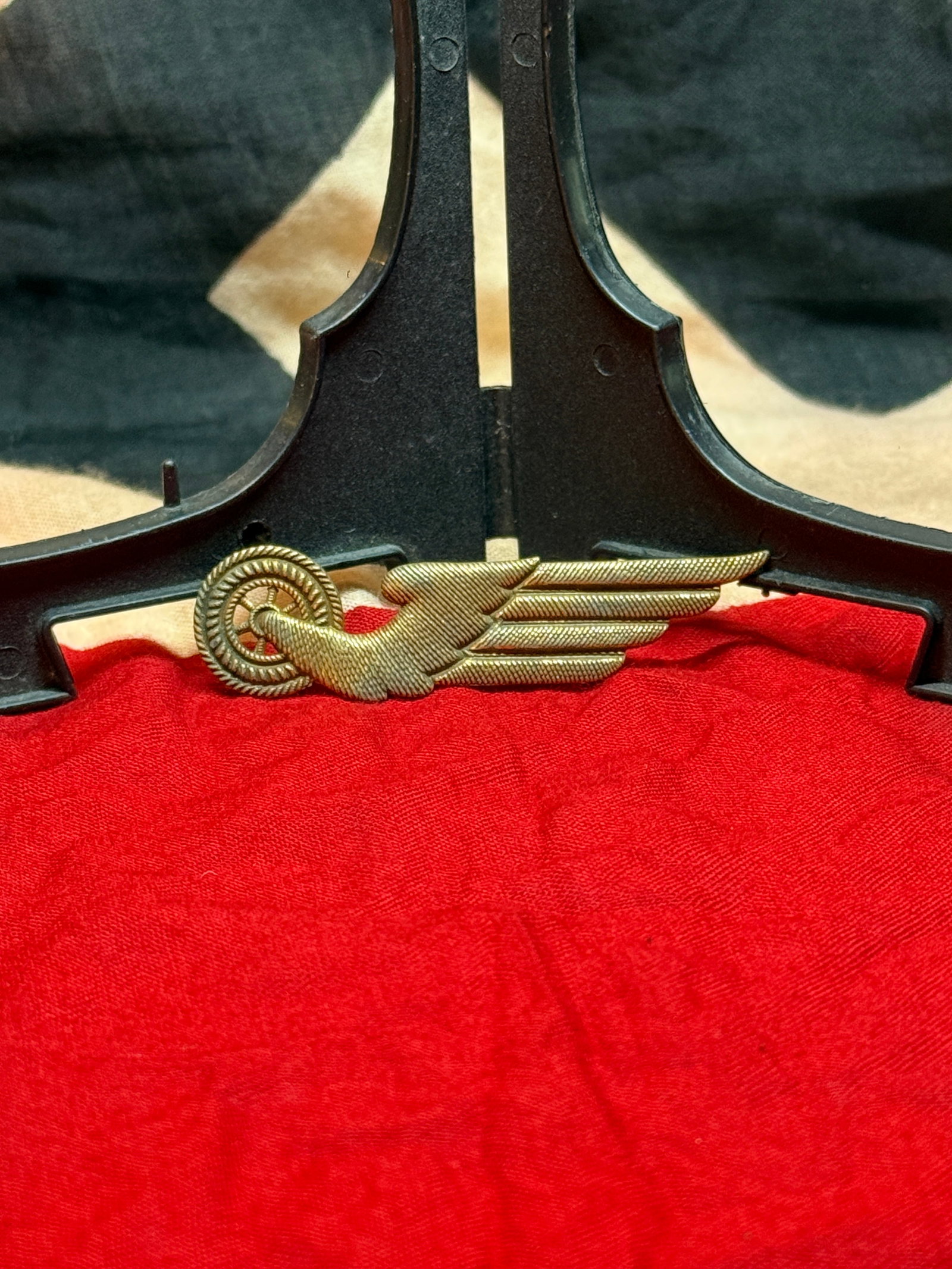 WWII German Transportation Service Winged Wheel Insignia: This metal insignia displays the classic winged wheel, an internationally recognized symbol of transportation, mobility, and communications. Finely detailed feathers extend from a spoked wheel, creati
