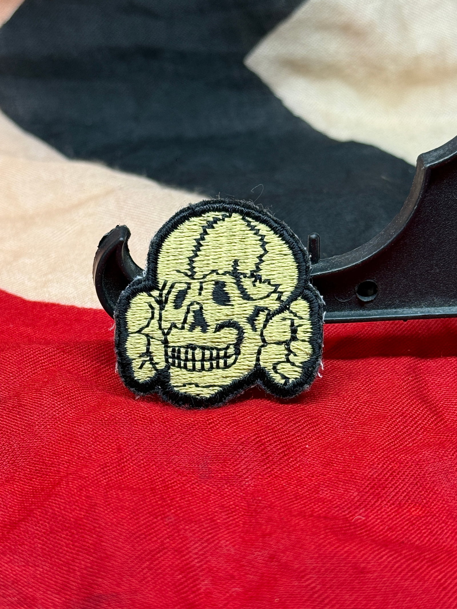 WWII German SS Totenkopf Skull Cloth Badge – Embroidered Uniform Insignia: WWII-era German SS Totenkopf cloth badge featuring the iconic skull design rendered in light-colored embroidery with black stitched detailing and border. The badge displays the recognizable Totenkopf 