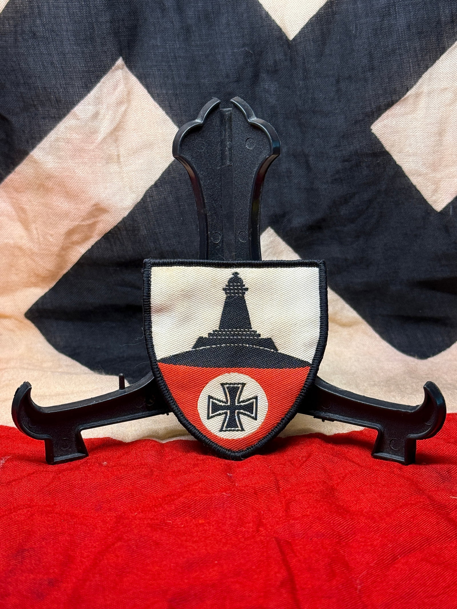 World War I German Kyffhäuser Veterans Association Sleeve Shield: Shield-shaped embroidered cloth insignia featuring the Kyffhäuser Monument above a black Iron Cross set against a red, white, and black field. The badge is edged with black embroidered trim and backe