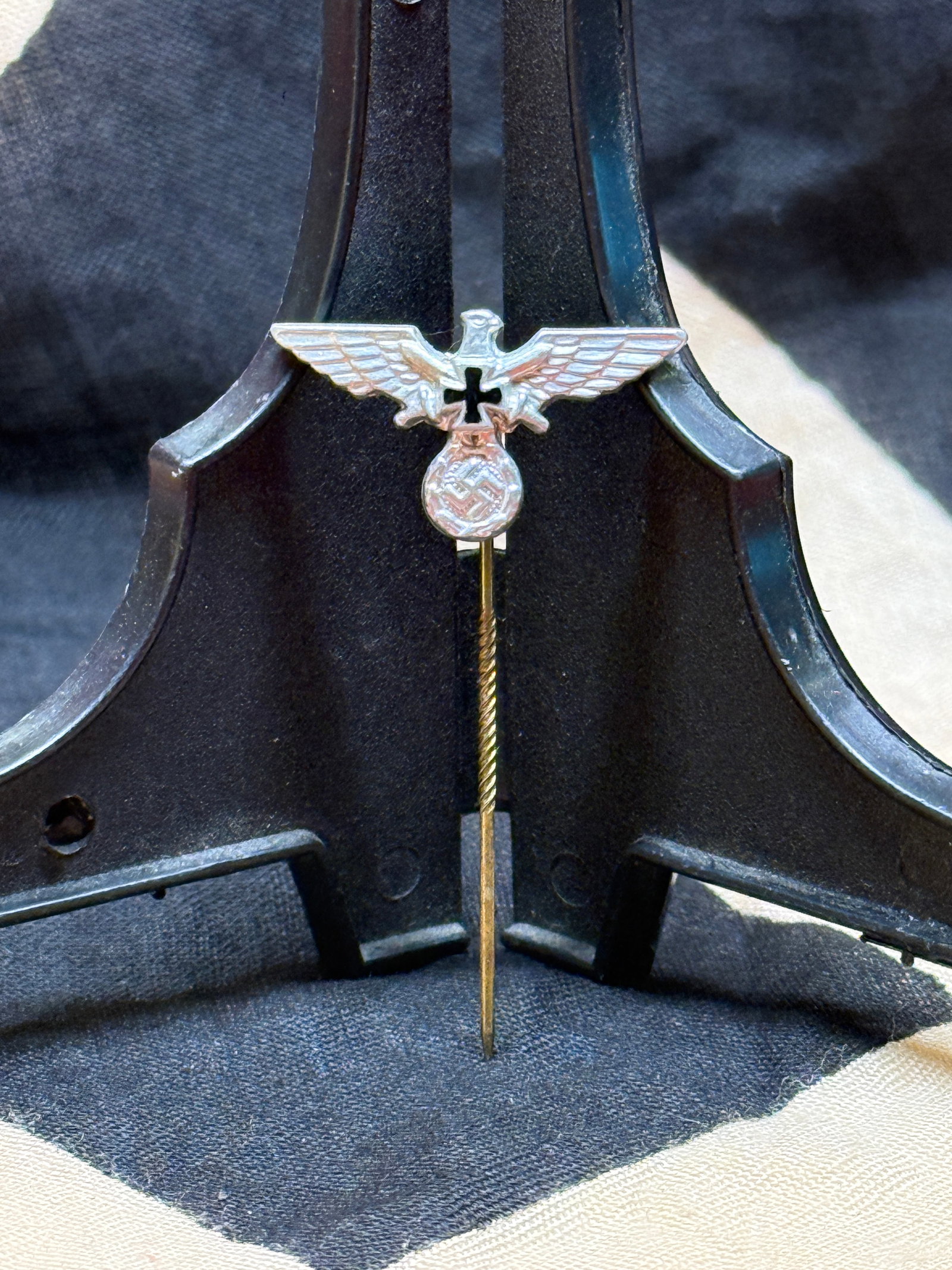 WWII German Patriotic Eagle Stickpin: This silvered metal stickpin depicts the German national eagle with outstretched wings above an Iron Cross and wreath enclosing a swastika. Designed for wear on civilian clothing, lapels, hats, or com