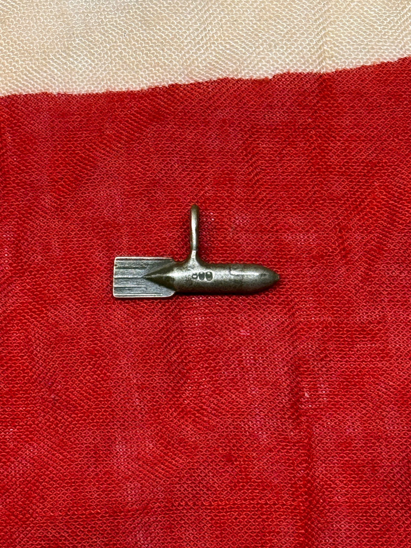 WWII German Ordnance-Themed Pendant: This small cast-metal pendant is fashioned in the form of a finned military projectile and incorporates an integral suspension loop for wear as a charm or personal accessory. Military-themed pendants 