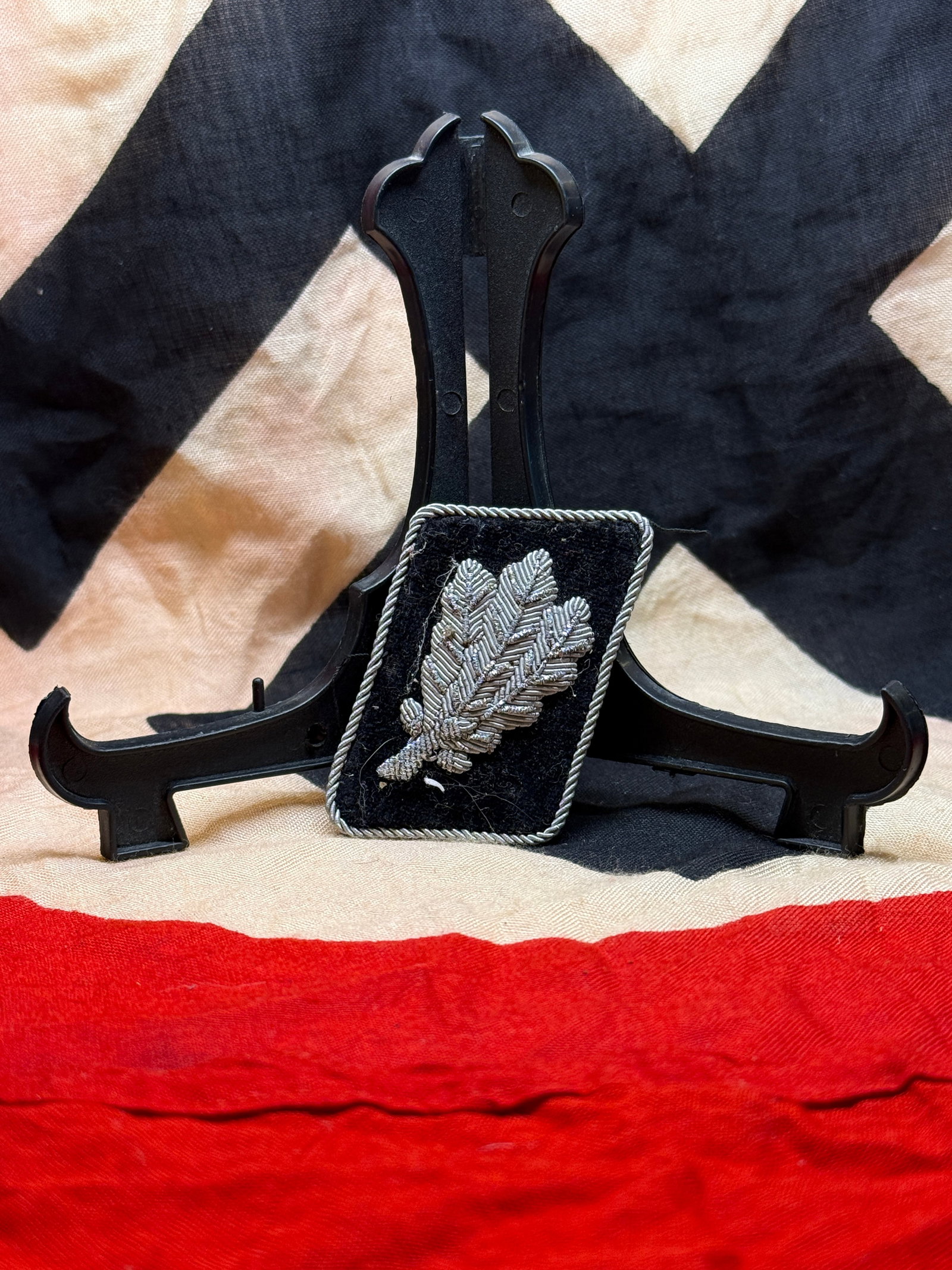 WWII German Waffen-SS Officer’s Oakleaf Collar Tab: This black velvet Waffen-SS collar tab displays finely executed silver wire oakleaf embroidery framed by twisted silver cord piping. Such insignia were worn by senior Waffen-SS officers and formed par