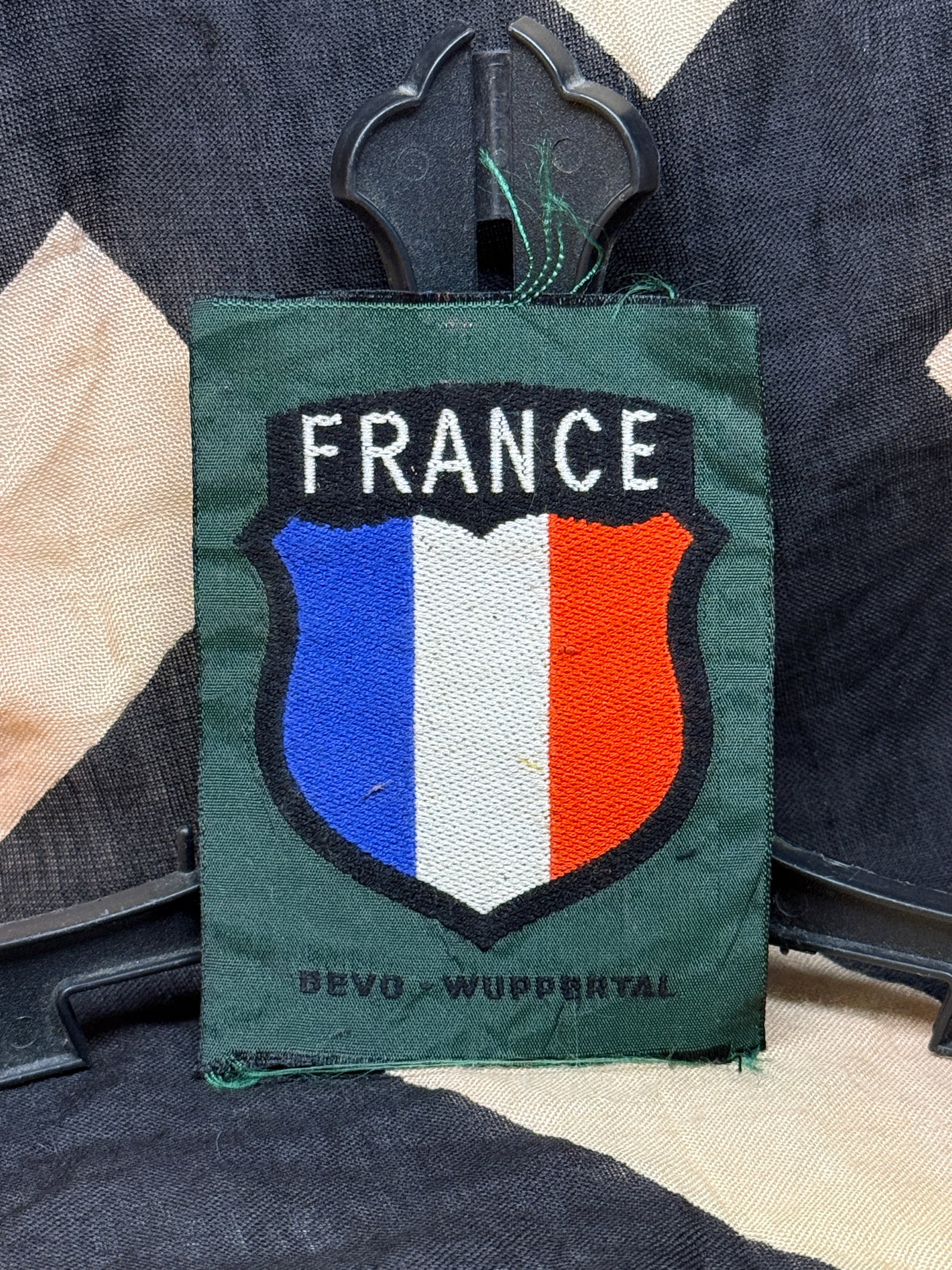 WWII Era German-France Volunteer Formation Sleeve Shield Patch – DEVO Wuppertal: German-France volunteer formation sleeve shield patch featuring the word "FRANCE" above a shield displaying the French tricolor in blue, white, and red. The patch is embroidered on a dark green backin