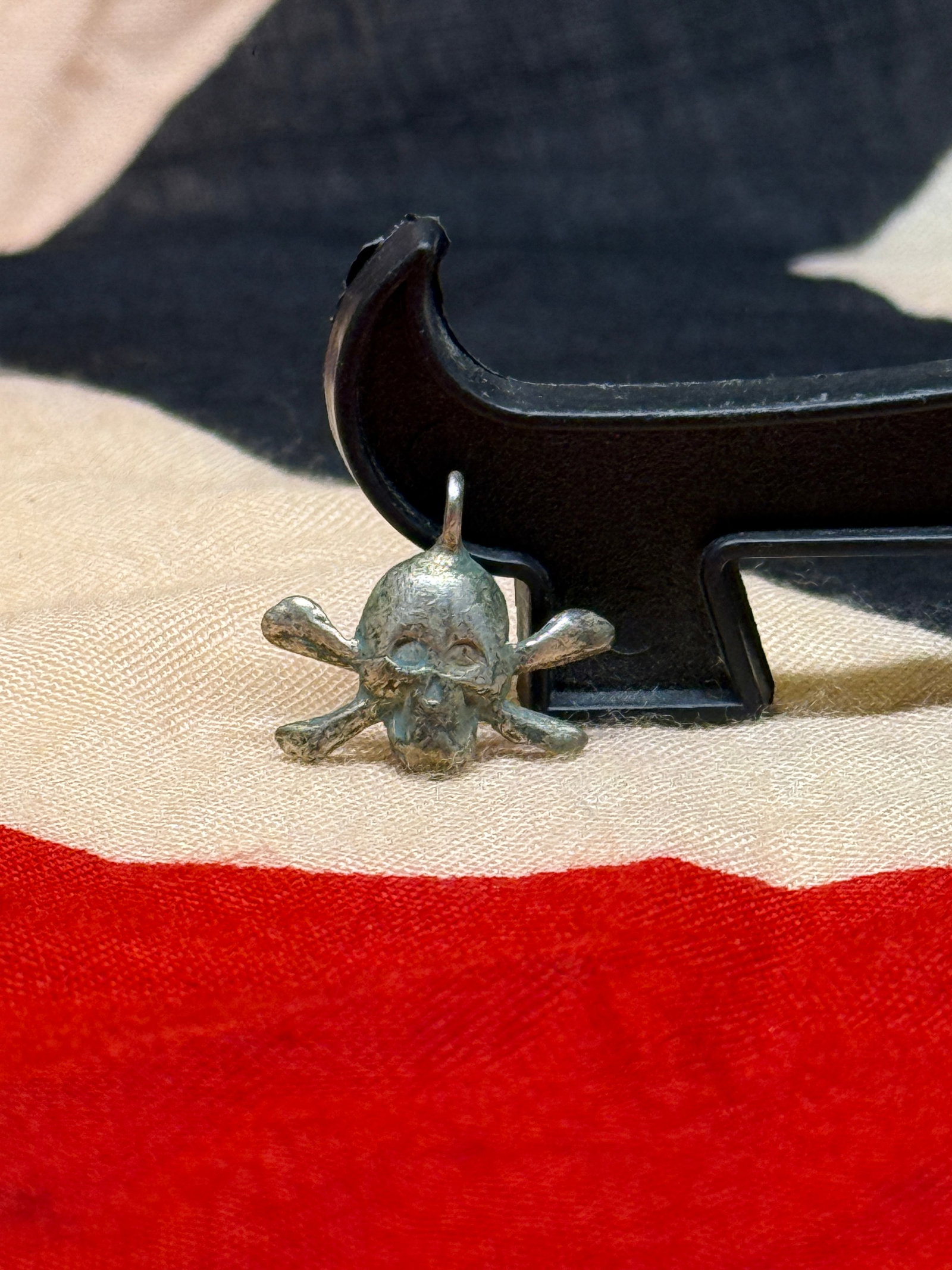 WWII Era German Totenkopf Skull Pendant with Crossbones Motif: This small cast-metal pendant depicts a skull above crossed bones, a motif historically associated with several European military traditions. Suspended from an integral loop, the emblem was designed f