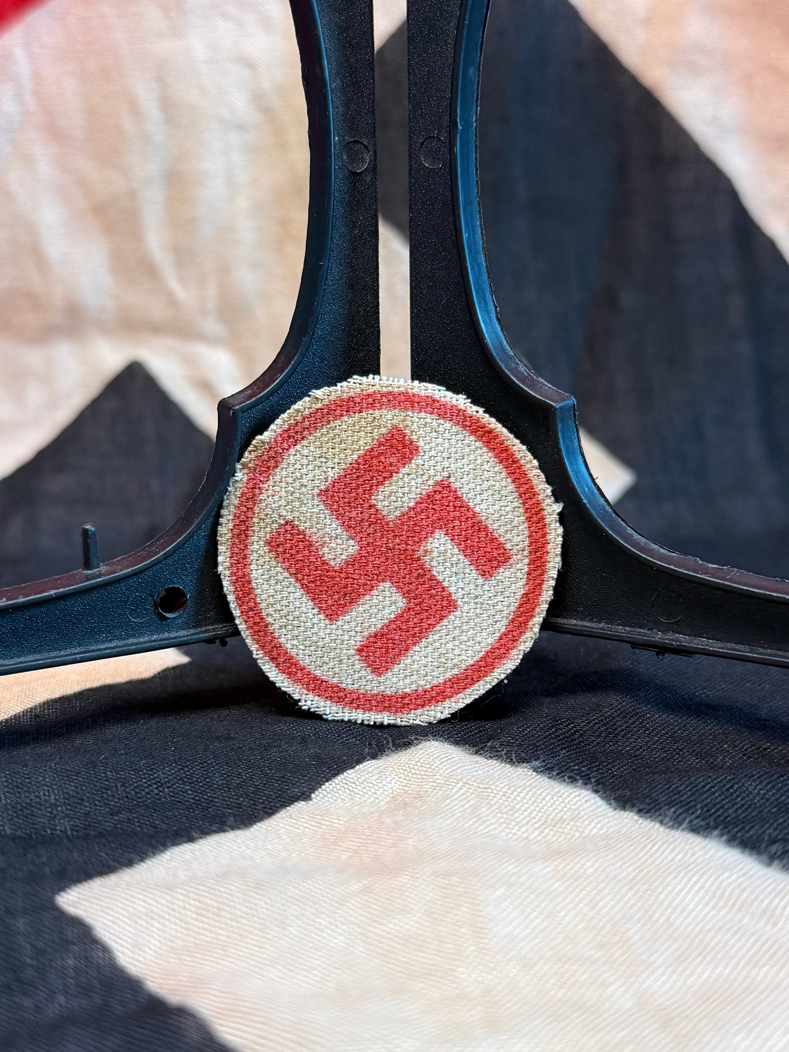 World War II German NSDAP Armband Roundel (Center Emblem): Circular woven cloth insignia featuring a red swastika on a white field surrounded by a red border. This textile roundel formed the central emblem sewn onto National Socialist German Workers’ Party 