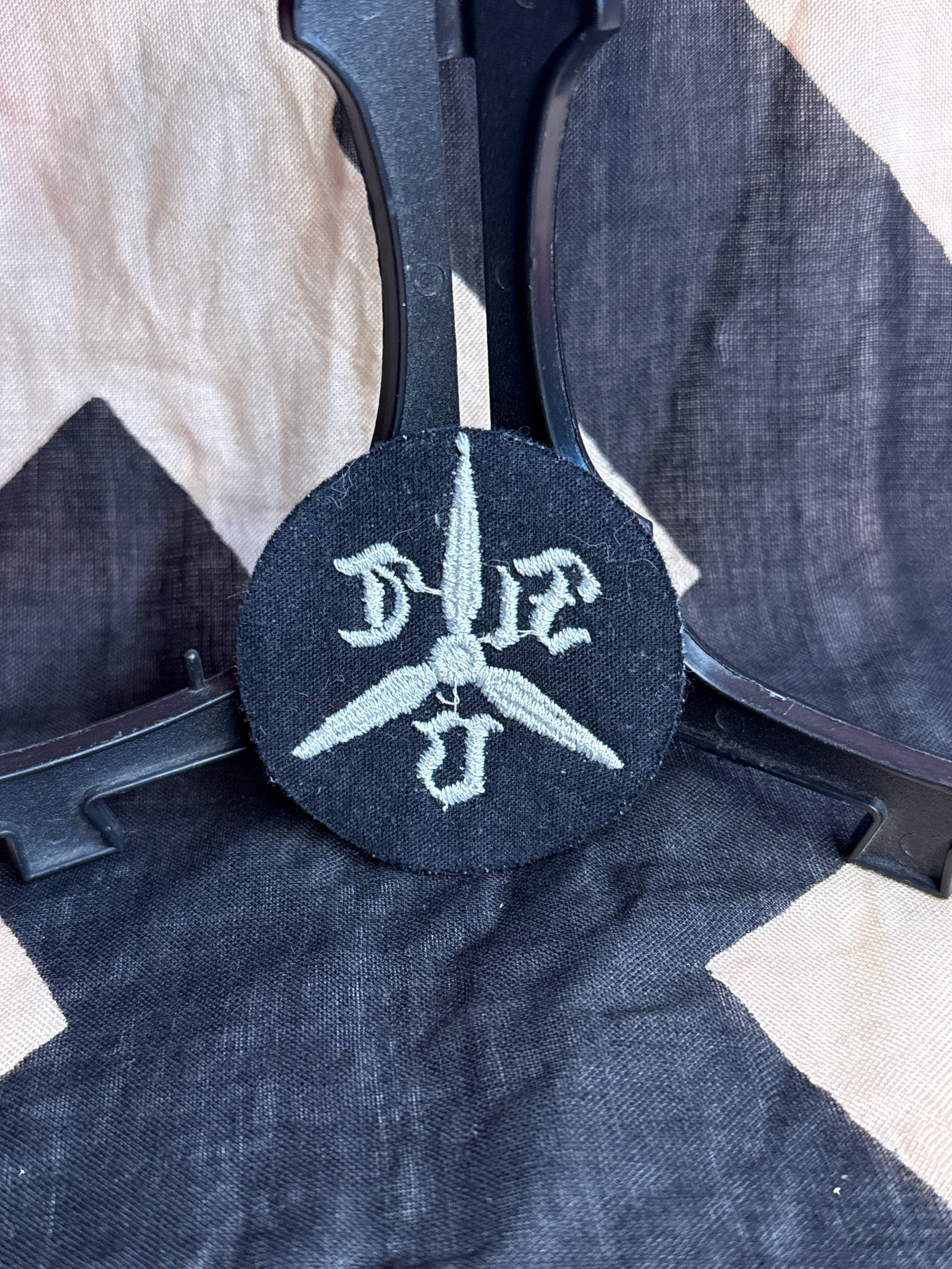 World War II German Luftwaffe Technical Flight School Sleeve Insignia: Circular embroidered cloth insignia executed in light gray thread on dark blue wool backing, displaying a three-bladed propeller flanked by Gothic-style letters. The propeller motif served as a symbol