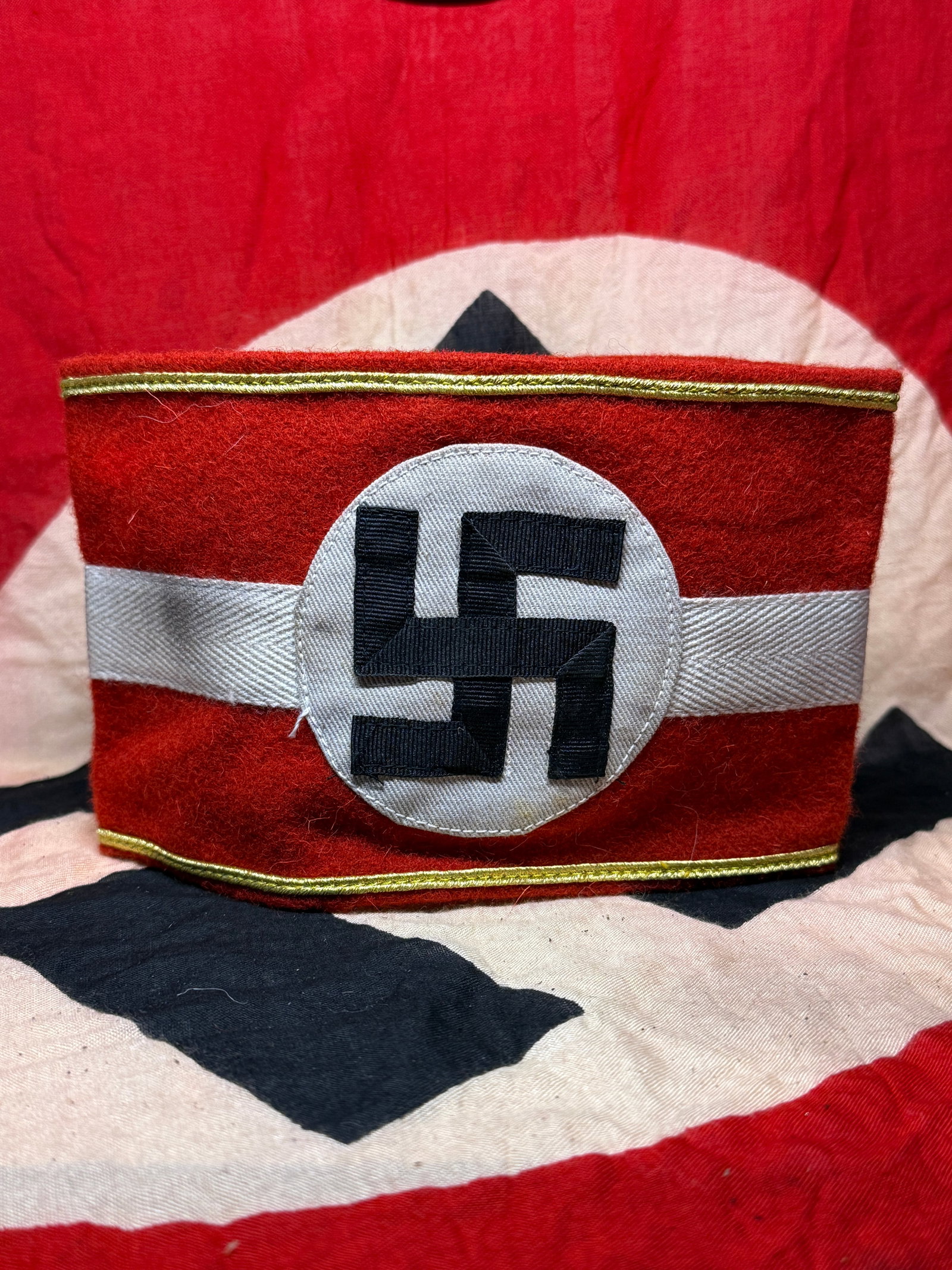 WWII NSDAP Political Leader Armband with RZM Label: This red wool armband features the black swastika on a white roundel, the principal political emblem associated with the National Socialist German Workers’ Party (NSDAP). The interior retains an ori