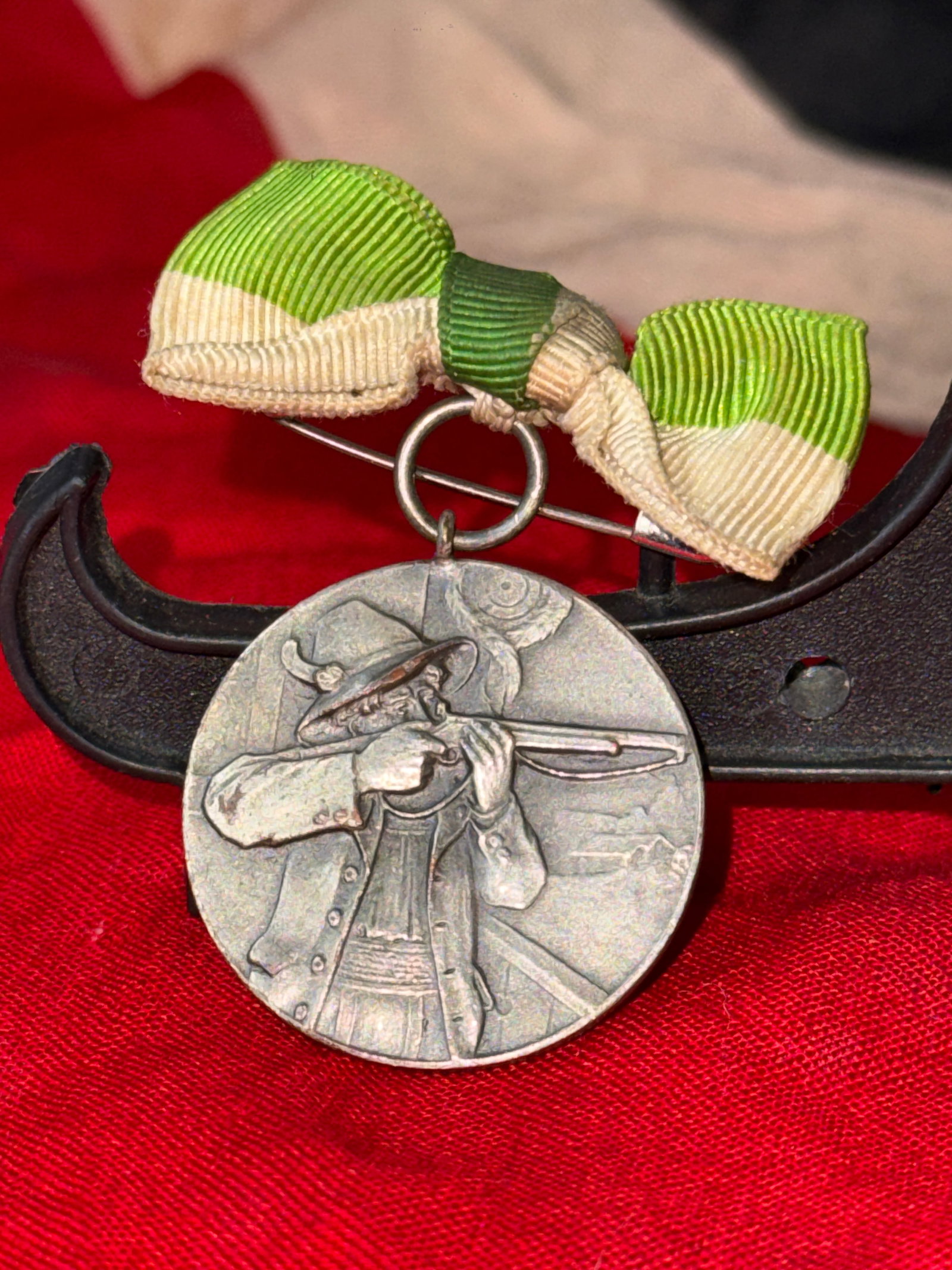 WWI German Commemorative Shooting Medal with Ribbon: This circular commemorative medal depicts a rifleman taking aim while wearing traditional German attire, symbolizing the long-standing marksmanship traditions of German shooting societies. Suspended f