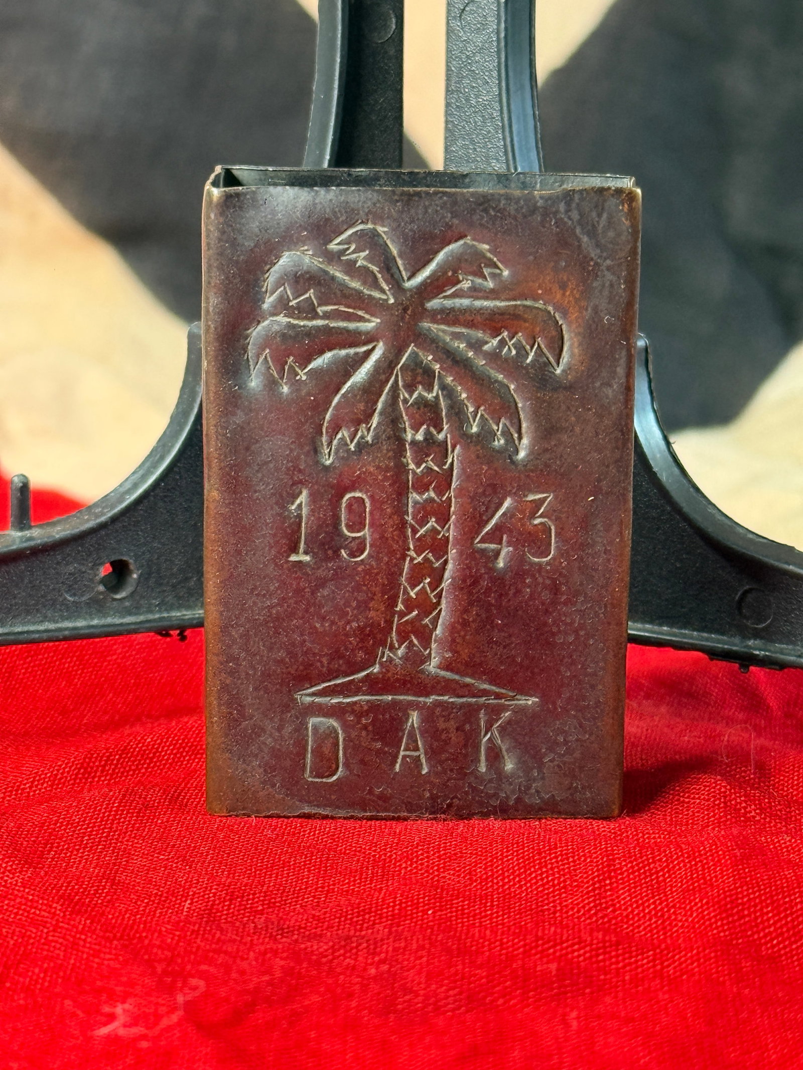 WWII German Afrika Korps DAK 1943 Trench Art Matchbox Cover: This embossed metal matchbox cover is decorated with a stylized palm tree above the initials "DAK" and the date "1943," identifying it with the Deutsches Afrikakorps (German Africa Corps). Fashioned t