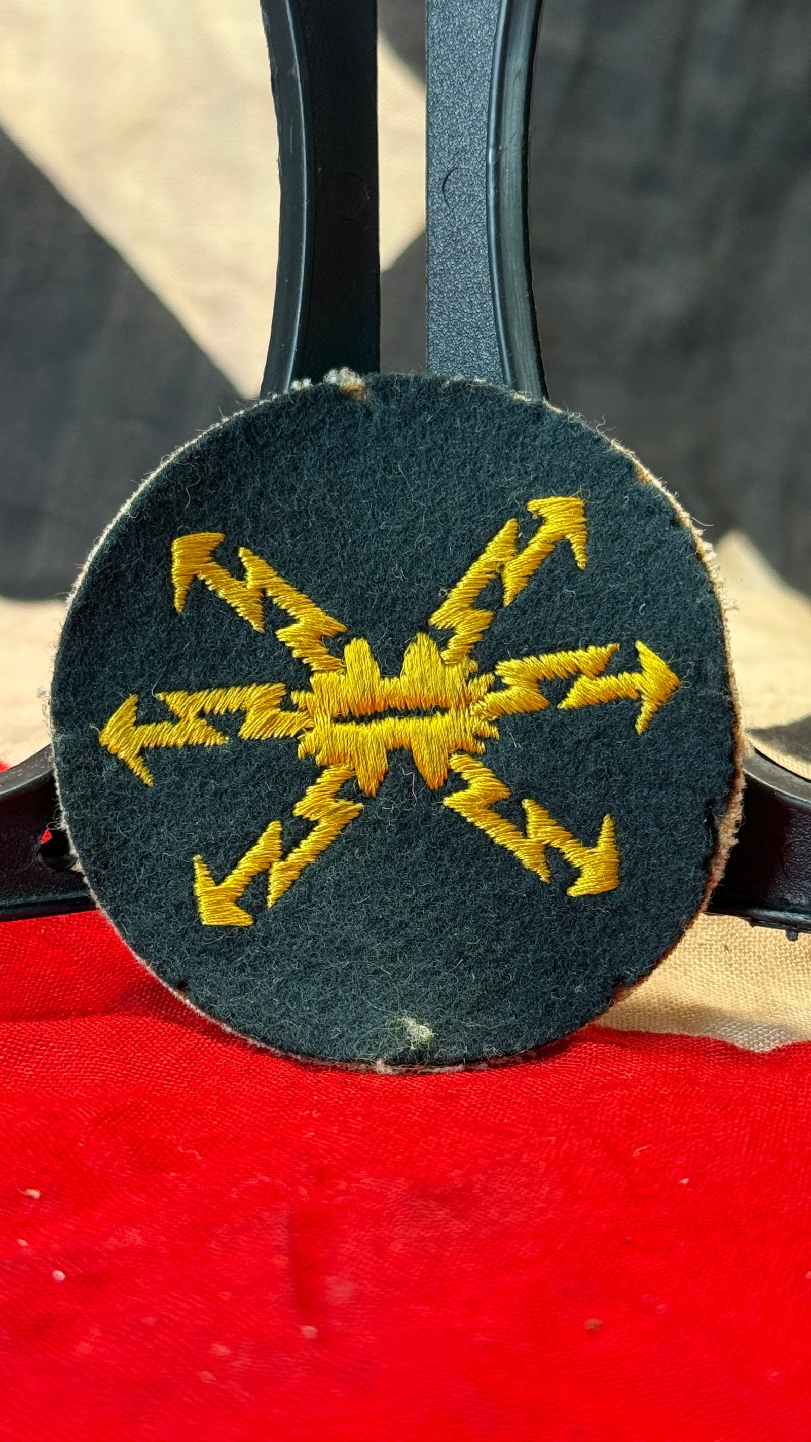 WWII German Wehrmacht Signals (Nachrichten) Sleeve Specialty Insignia: This circular dark wool sleeve insignia is embroidered with yellow lightning bolts radiating from a central communications device, the traditional branch symbol of the German Army Signals (Nachrichten