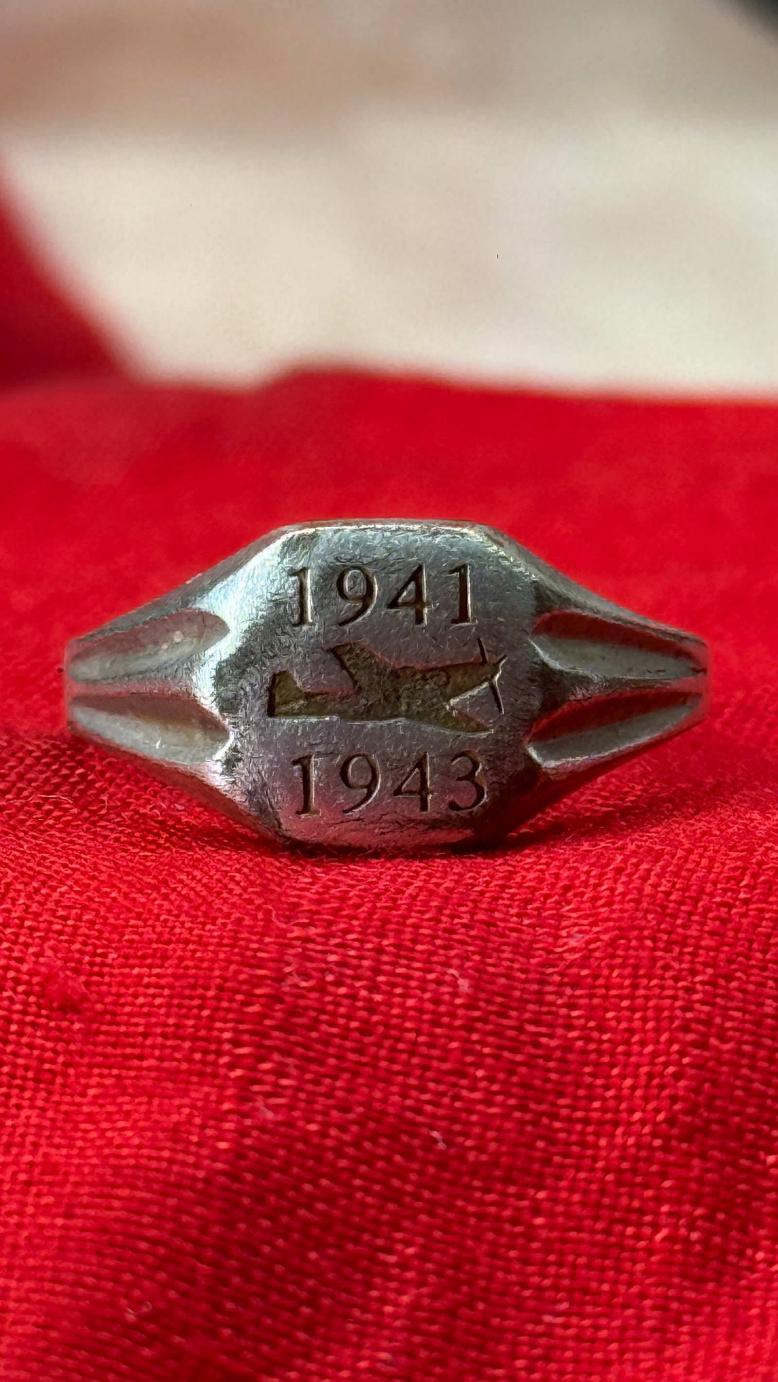 WWII German Luftwaffe Aircraft Ring Worn By Aircraft Personel: This silver-colored ring features a military aircraft engraved between the dates "1941" and "1943" on its oval bezel. The tapered shoulders incorporate fluted styling characteristic of wartime souveni