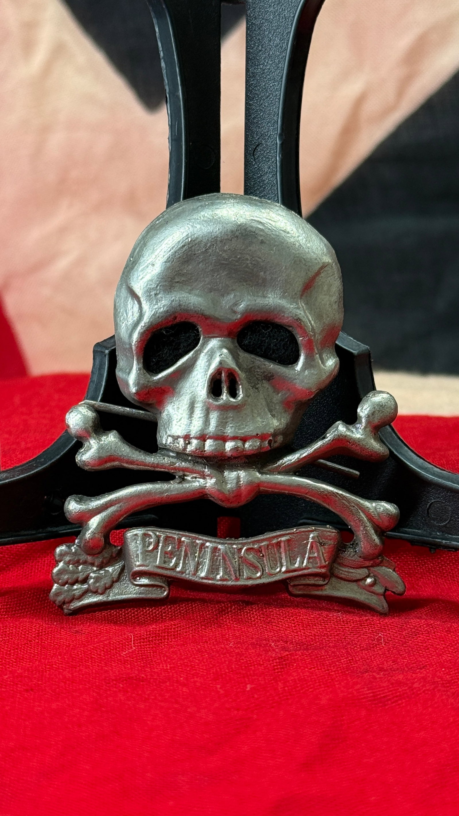 WWII German SS Skull and Crossbones "PENINSULA" Badge: This World War II German skull and crossbones badge features a detailed Totenkopf above crossed bones with an integral scroll bearing the inscription "PENINSULA." The reverse retains its original wire