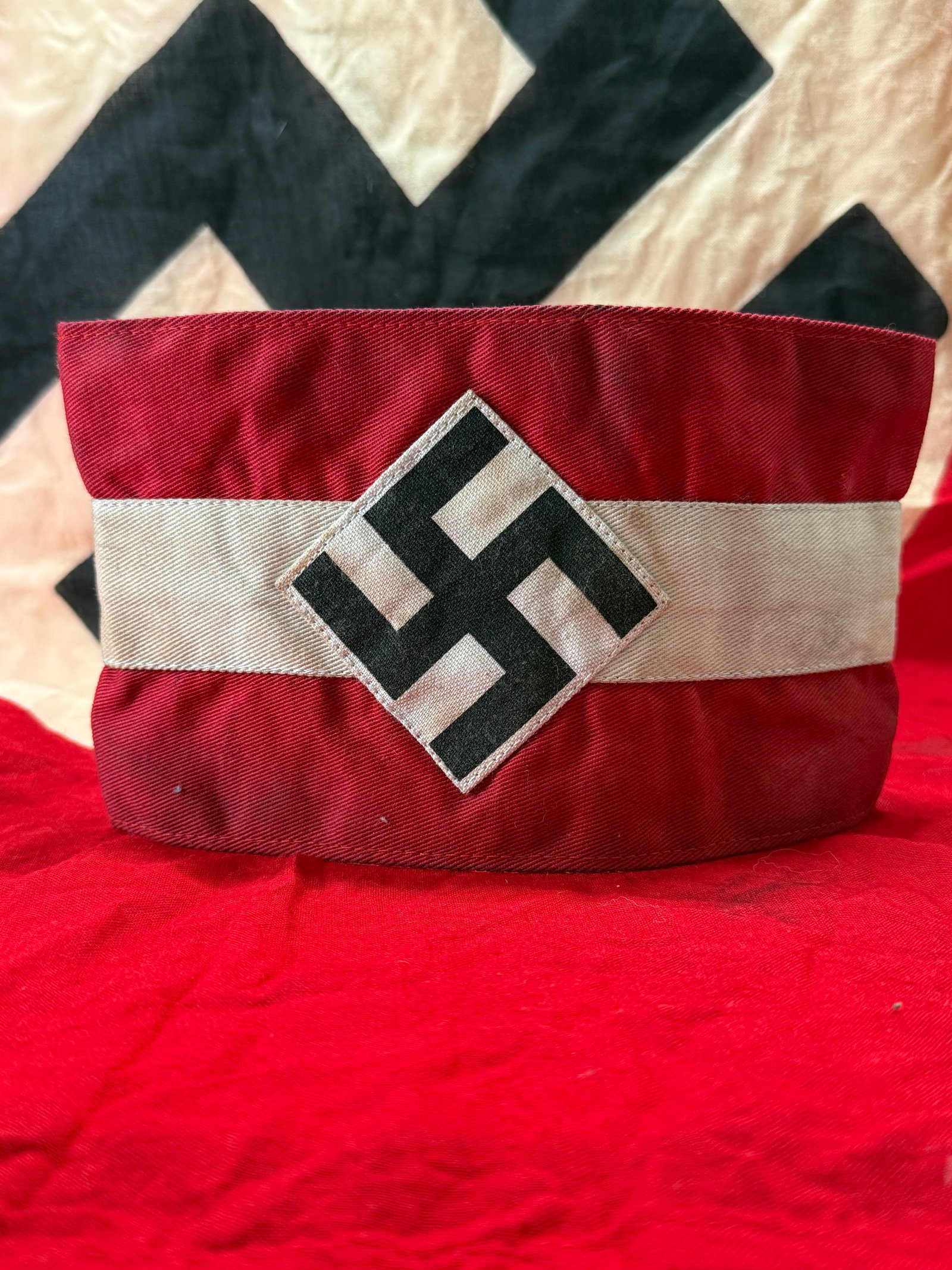 WWII German Hitler Youth Armband with RZM Manufacturer Tag: This World War II German Hitler Youth (Hitlerjugend) armband is constructed of red cloth with a white center band and a separately applied diamond bearing the black swastika emblem. The interior retai