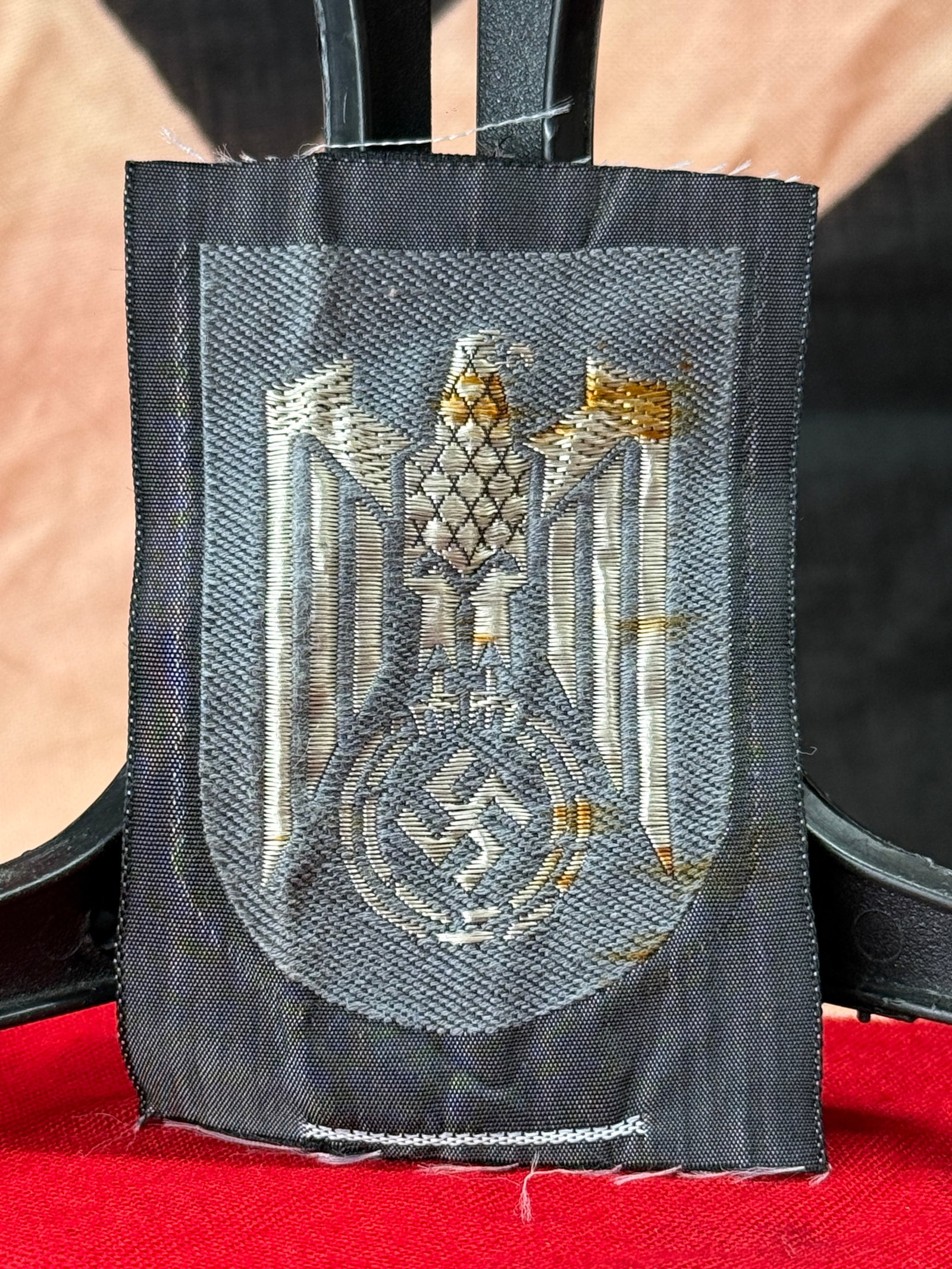 WWII German DRK National Eagle Sleeve Shield Insignia: This woven sleeve shield was worn by members of the Deutsches Rotes Kreuz (German Red Cross) during the Second World War. The design depicts the national eagle with outstretched wings above a wreath e