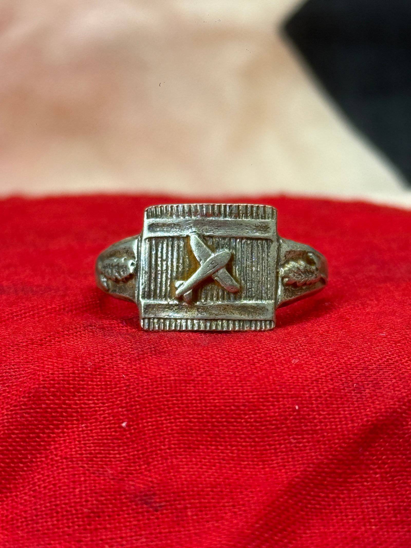 WWII German Luftwaffe Glider Pilot's Silver Ring: This WWII German Luftwaffe Pilot's silver ring features a rectangular face displaying a raised aircraft in flight set against a finely lined background. The shoulders are decorated with detailed oak l