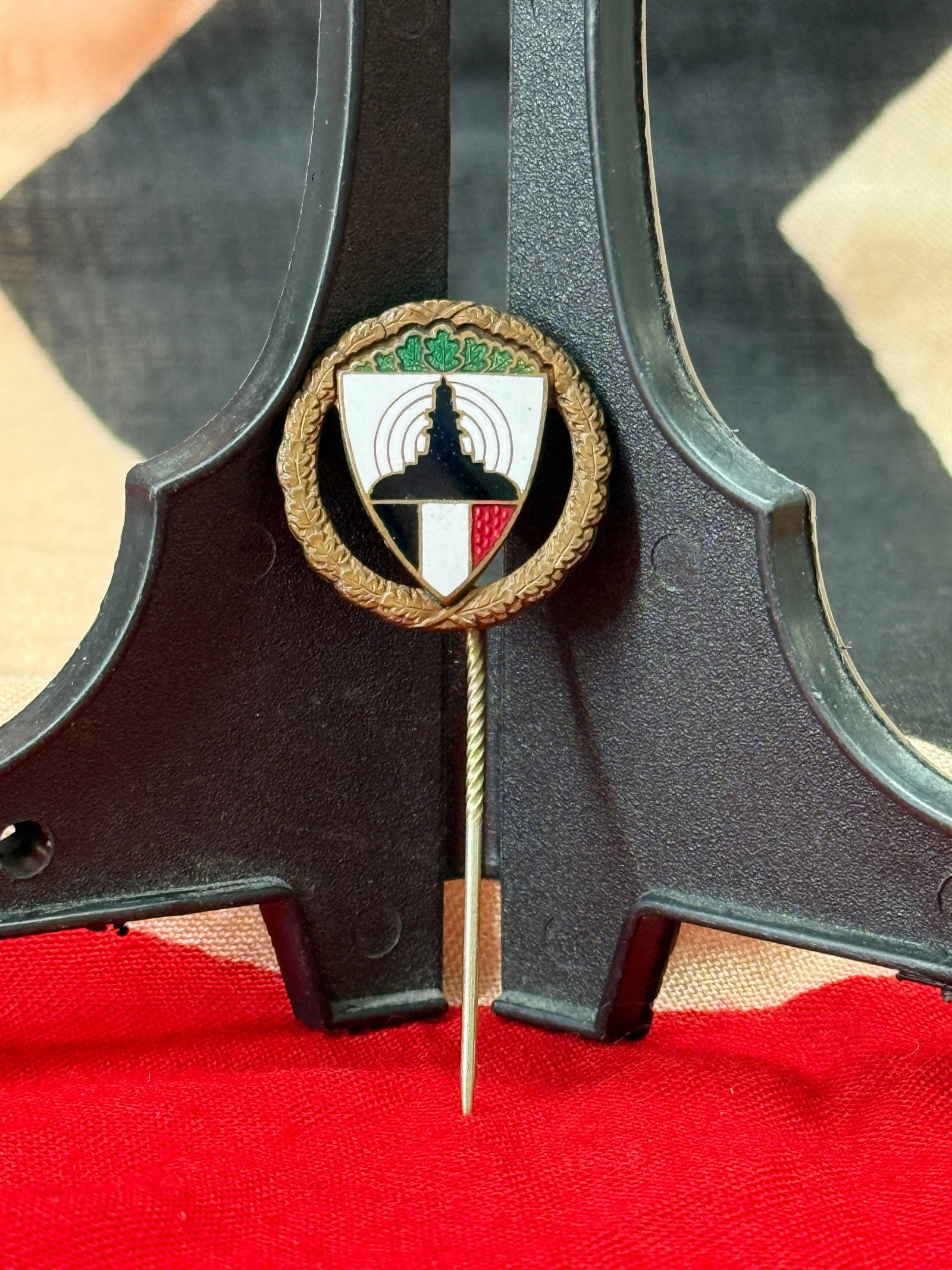 WWII German Kyffhäuserbund Shooting Award Stickpin: This enameled German stickpin features a decorative laurel wreath surrounding a shield with stylized shooting imagery and is mounted on a twisted stickpin shaft. The reverse bears the legal protection