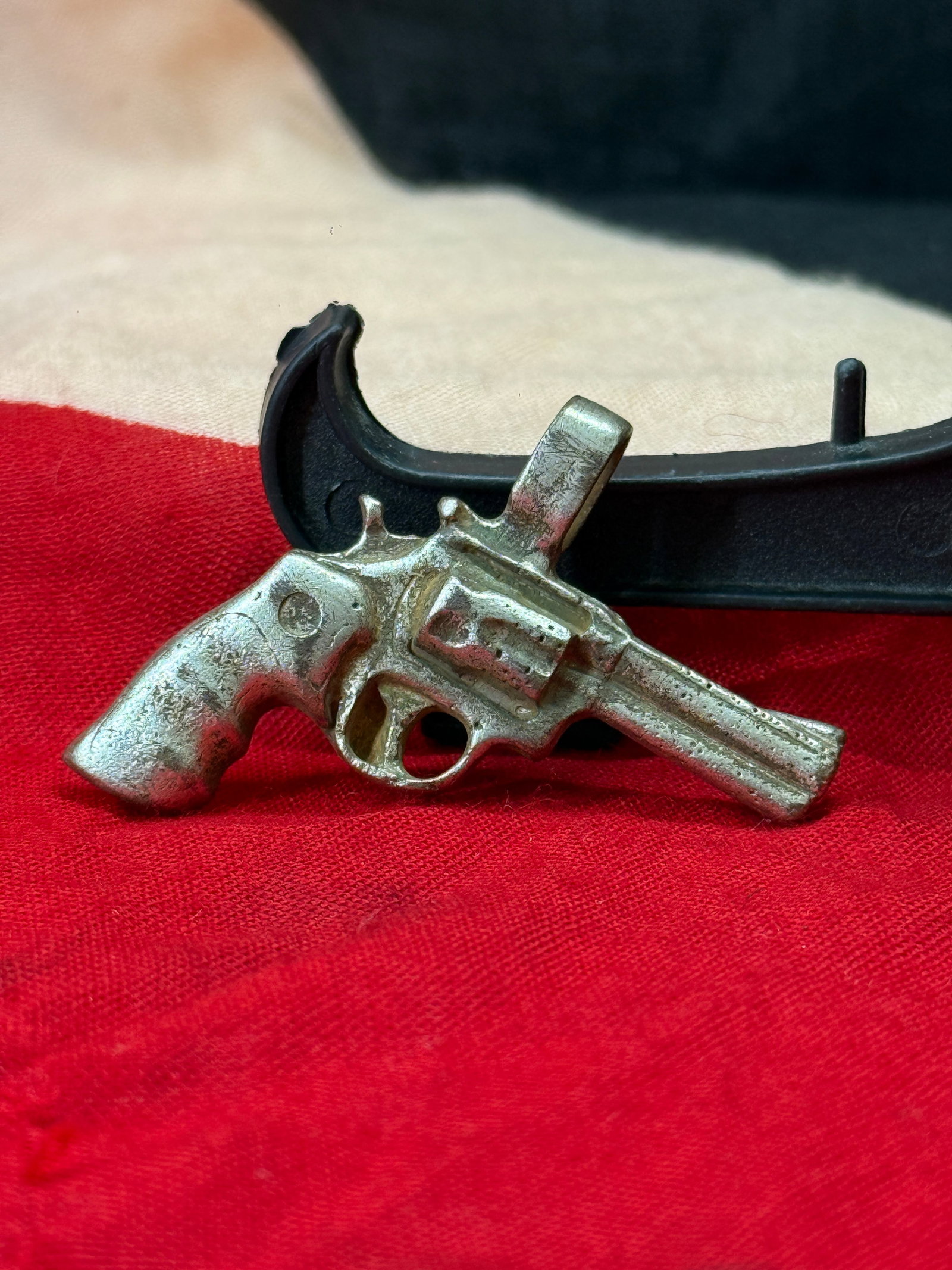 WWII German Miniature Revolver Charm Pendant: This miniature silver charm is cast in the form of a small revolver with molded cylinder, barrel, grip, and trigger details. A suspension loop is incorporated into the top, indicating it was intended 