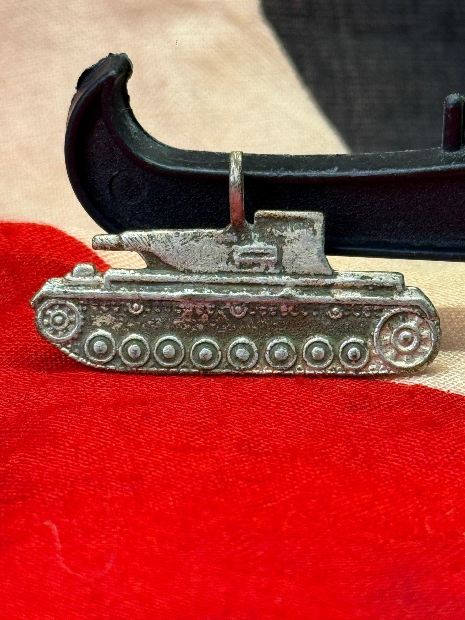 WWII German Sturmgeschütz III (StuG III) Charm Silver Pendant: Silver pendant depicting a German Sturmgeschütz III self-propelled assault gun in profile, complete with detailed running gear, road wheels, and armored superstructure. The reverse is stamped "B.H. M
