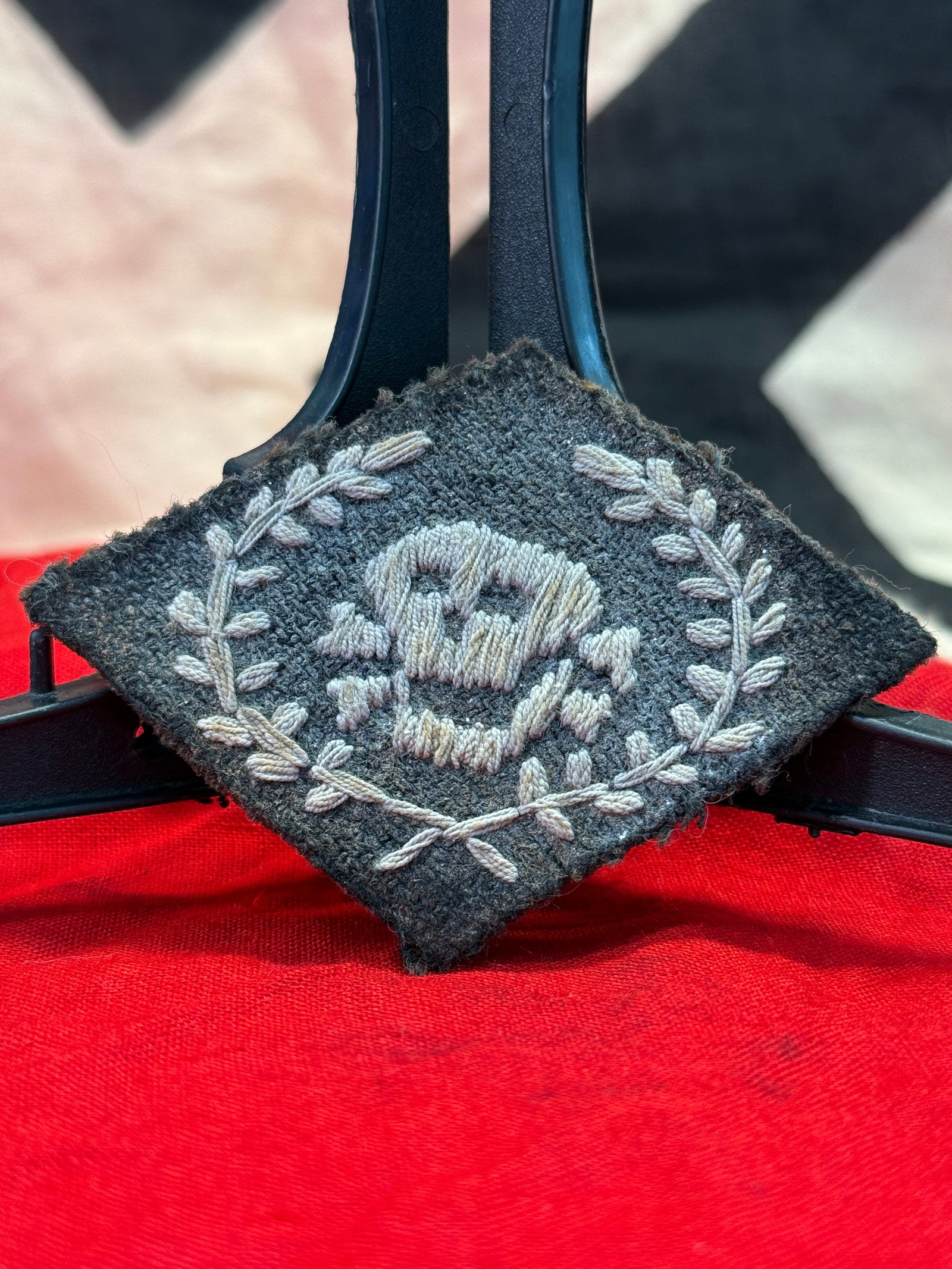 WWII German Waffen-SS Totenkopf (Death's Head) Collar Tab: Black wool collar tab embroidered with the distinctive Waffen-SS Totenkopf (Death's Head) insignia in silver-gray thread, enclosed within an embroidered wreath. The reverse displays period-style stitc