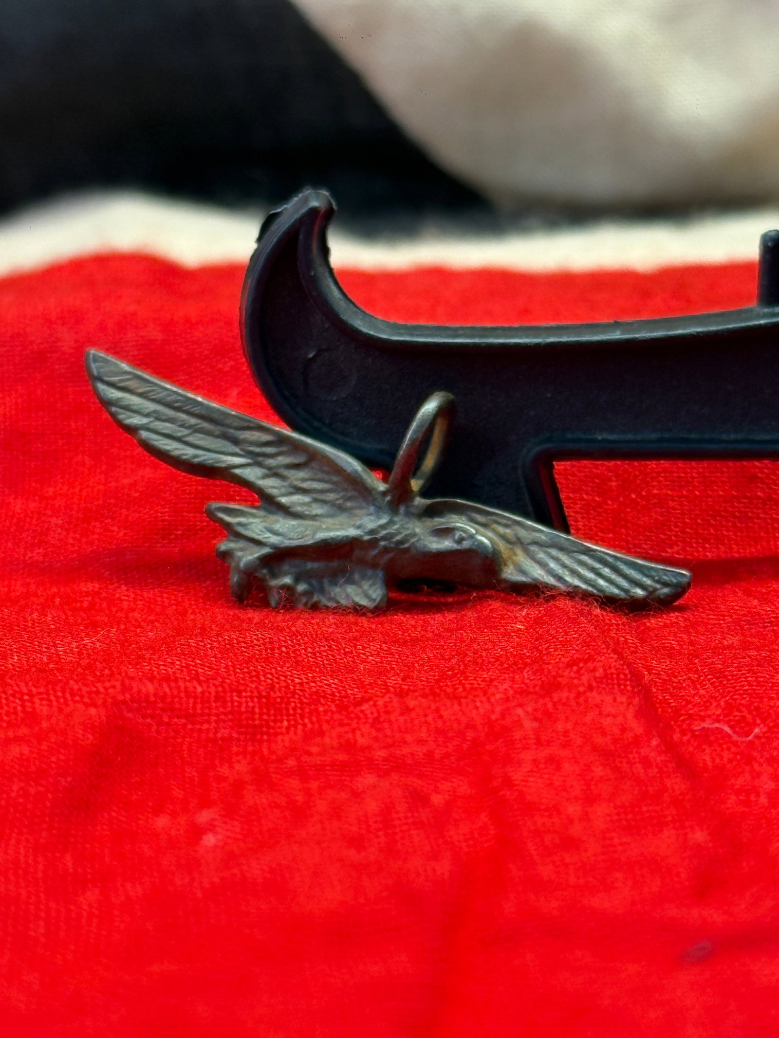 WWII German Luftwaffe Silver Eagle Pendant: Silver pendant depicting the outstretched Luftwaffe eagle clutching a central wreath, fitted with an integral suspension loop for wear as a necklace or charm. The reverse is stamped "GES. GESCH." indi