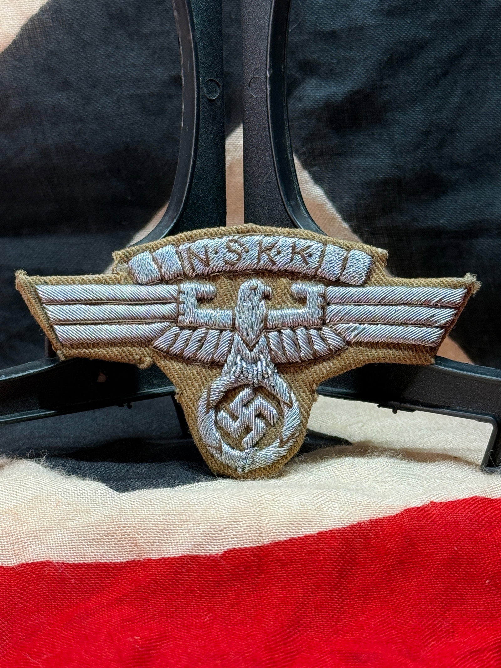 WWII German NSKK National Socialist Motor Corps Sleeve Eagle Insignia: This embroidered insignia displays the spread-wing eagle above the initials "NSKK," representing the Nationalsozialistisches Kraftfahrkorps (National Socialist Motor Corps). Executed in silver-gray th