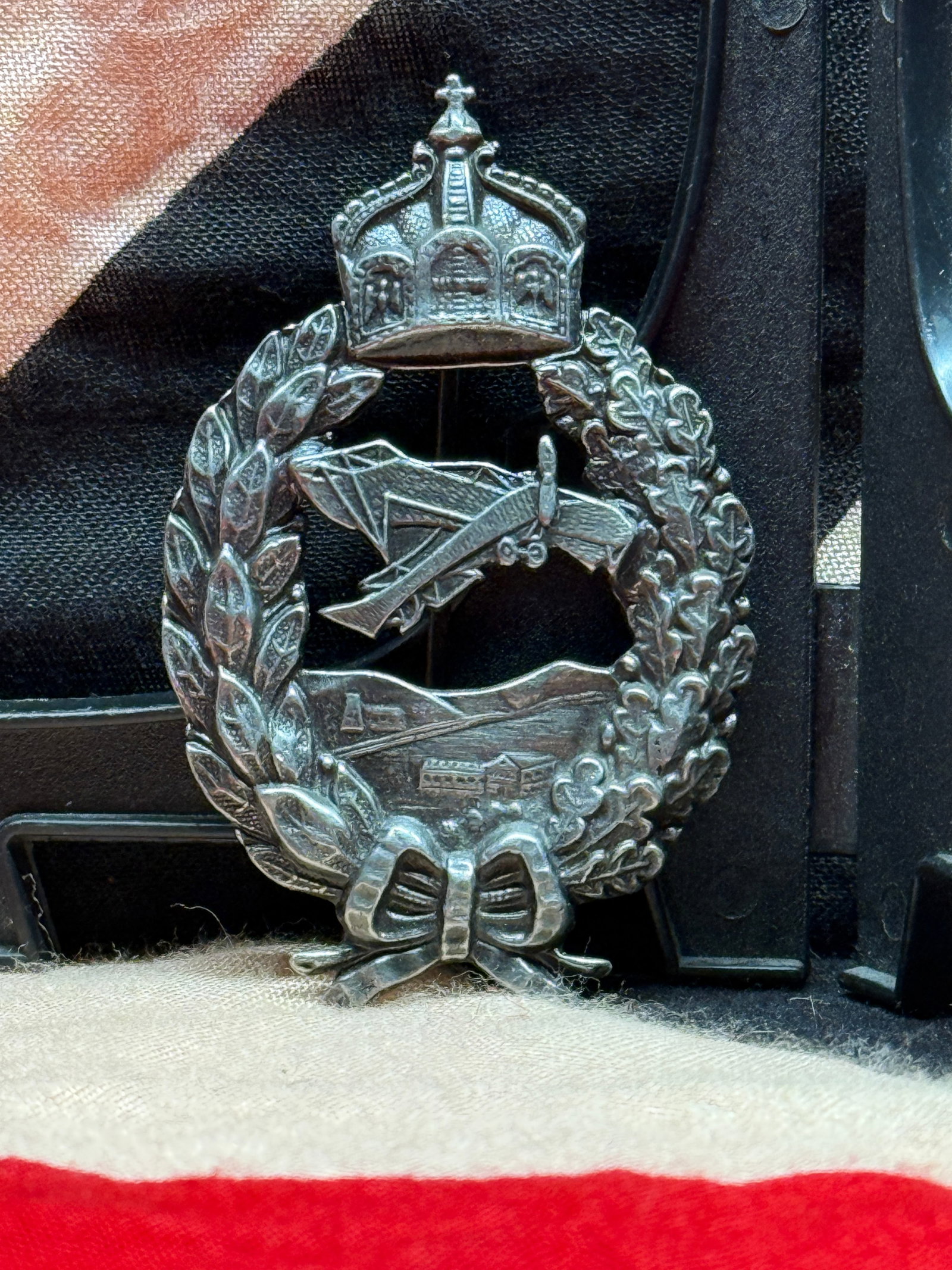 WWI Imperial German Prussian Military Pilot Badge: This silvered badge features the Imperial German crown above a laurel wreath enclosing an aircraft in flight over a landscape scene. The reverse retains its original vertical pin and catch assembly, c