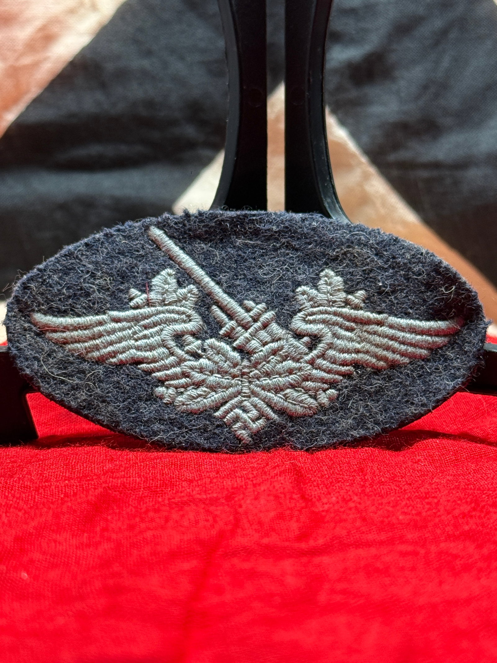 WWII German Army Motorized/Transport Sleeve Insignia: This WWII German cloth sleeve insignia features a machine-embroidered eagle with crossed sword/motorized motif on dark wool backing. The oval construction, gray thread, and service-worn fabric surface
