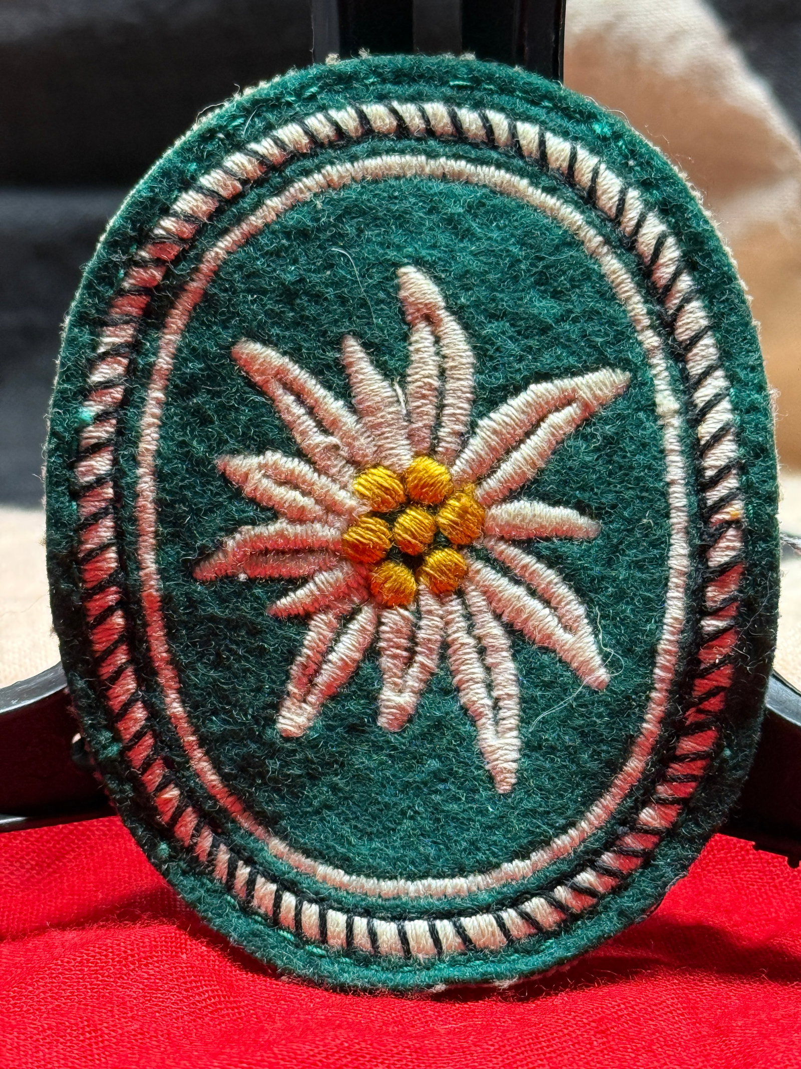 WWII German Gebirgsjäger Edelweiss Sleeve Insignia Patch: This WWII German Gebirgsjäger Edelweiss Sleeve Insignia Patch features the iconic embroidered Edelweiss flower with white petals and a yellow center on a dark green wool oval backing. The reverse dis