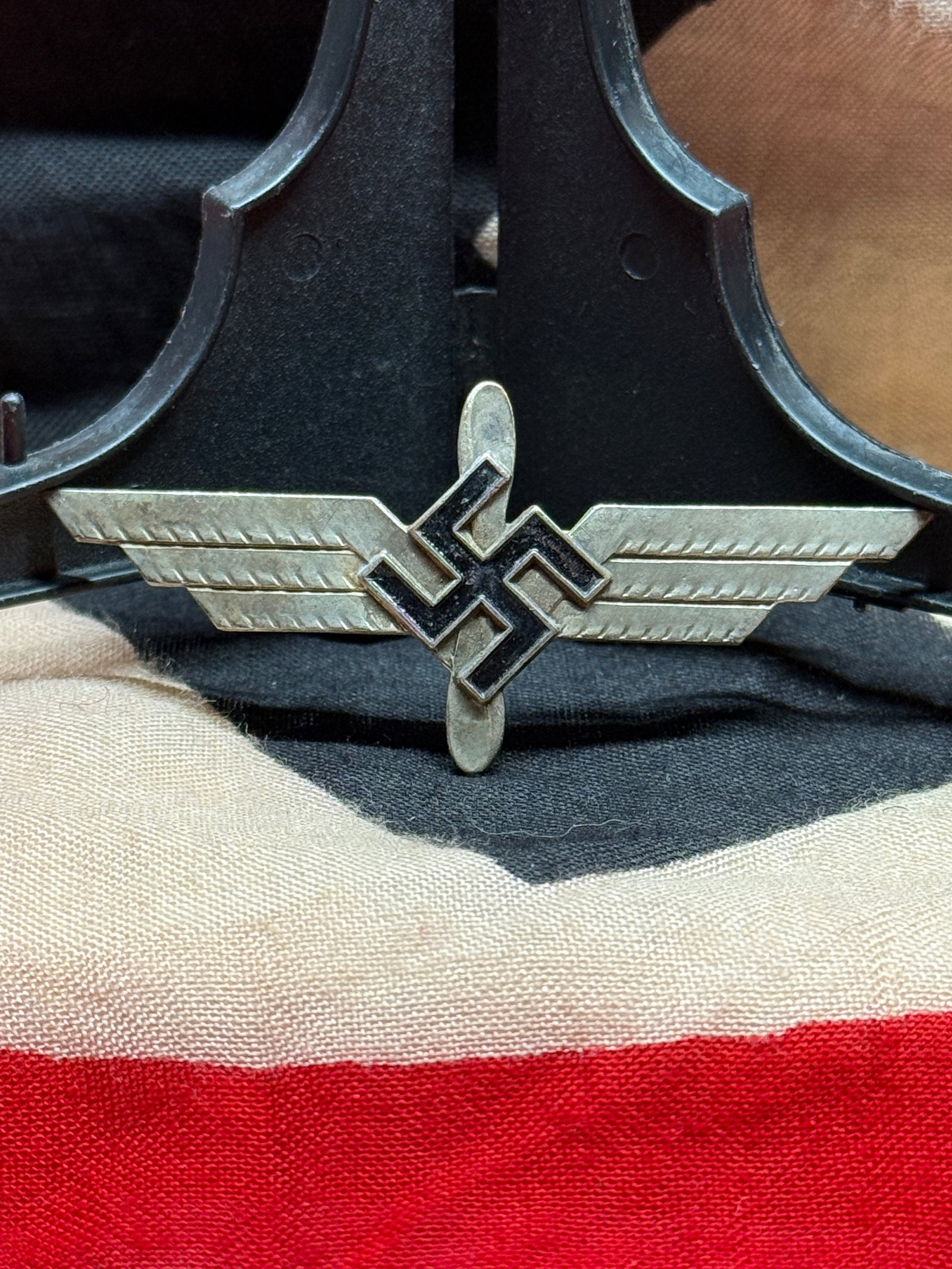 WWII German SA Brownshirt Winged Swastika Lapel Pin: This lapel pin features a stylized winged swastika motif executed in silvered metal with a horizontal pinback attachment. Small insignia of this style were worn by members and supporters of the Sturma