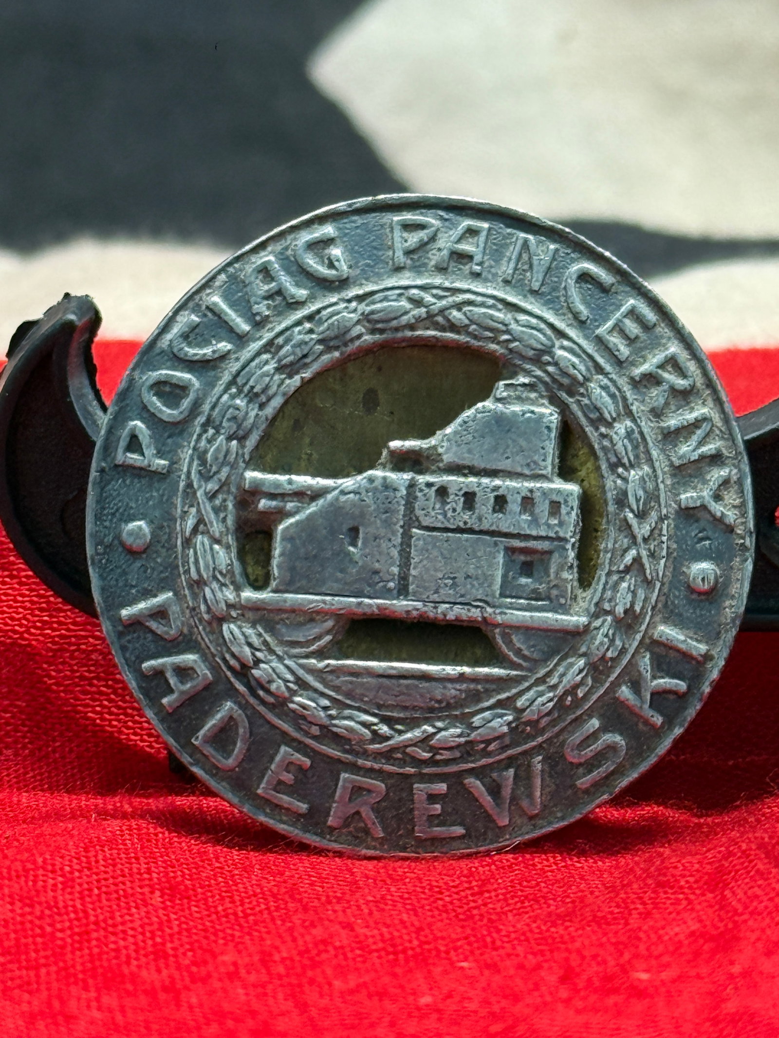 WWII German Panzerwaffe Armored Troops Badge by A. Panasiuk, Warszawa: This circular metal badge displays the inscription "Poci?g Pancerny Paderewski" surrounding the image of an armored train, with the reverse bearing the maker's mark of A. Panasiuk, Warszawa. Armored t