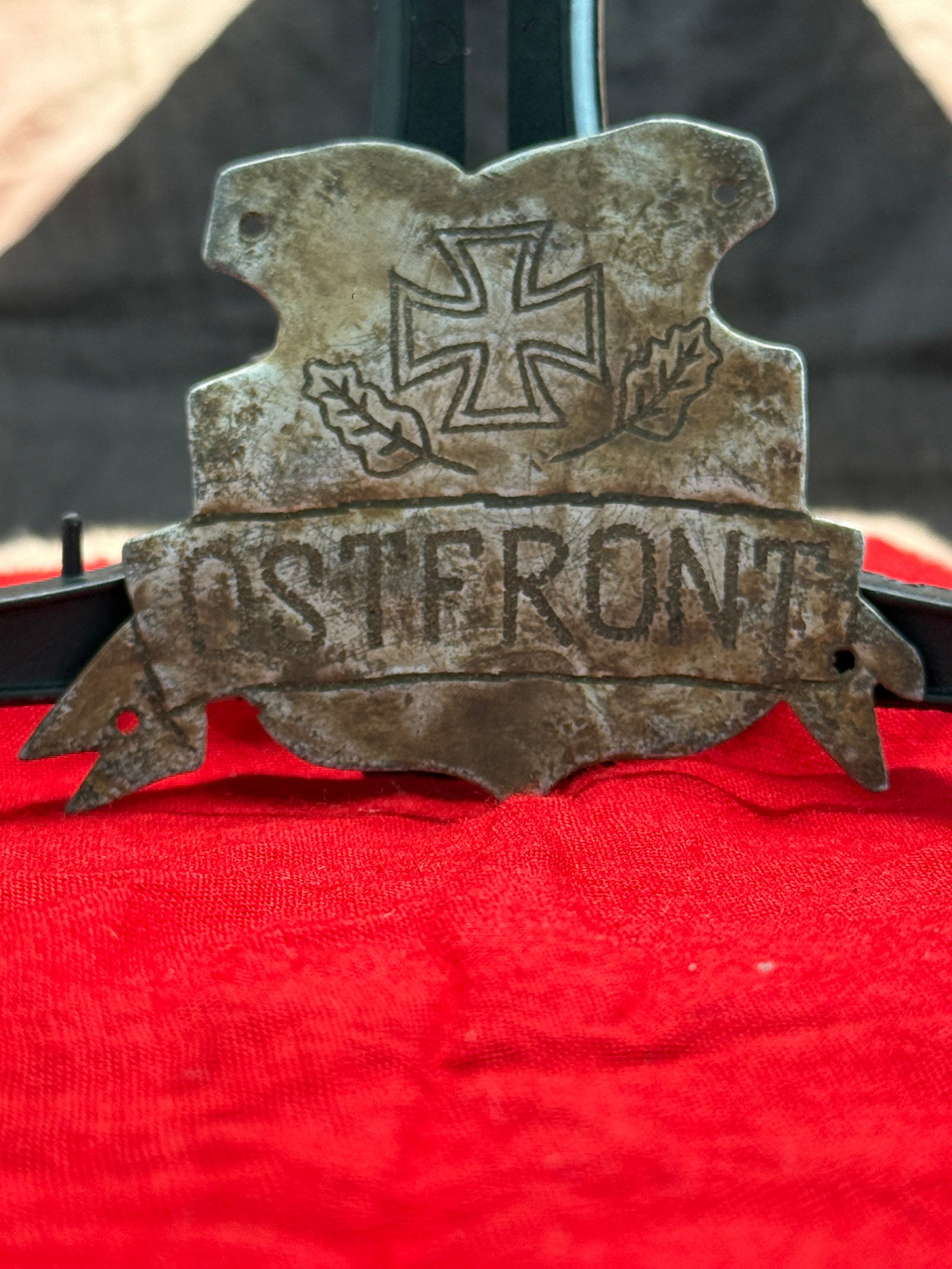 WWI German Austro-Hungarian “Ostfront?? Trench Art Plaque: This hand-cut metal plaque is engraved with an Iron Cross flanked by oak leaves above the large inscription “OSTFRONT” (Eastern Front). Pierced mounting holes suggest it was once attached to a