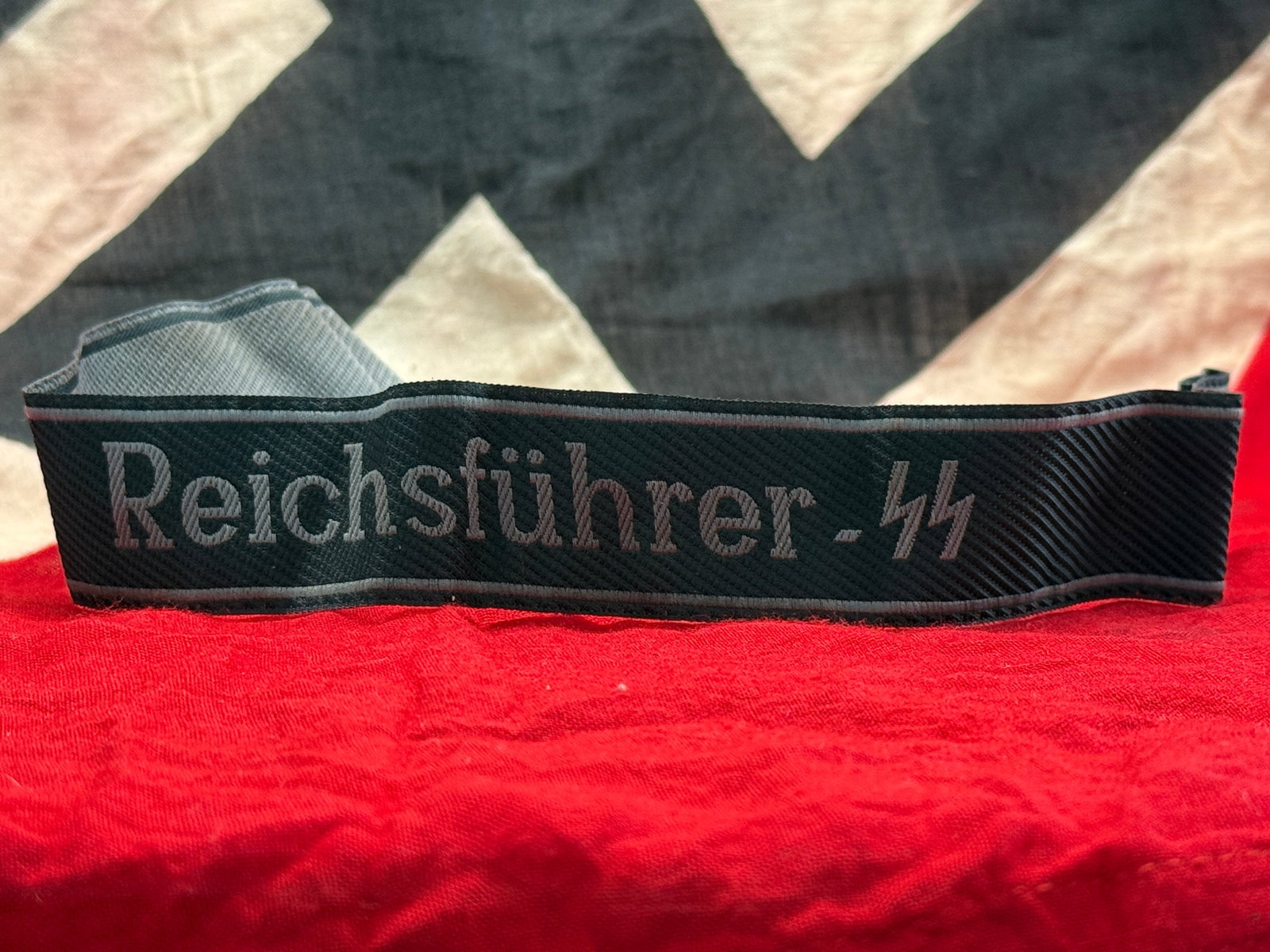 WWII German Waffen-SS “Reichsführer-SS?? Cuff Title: This woven black cuff title displays the machine-embroidered inscription “Reichsführer-SS” in silver-gray thread, with matching edge borders and period-style construction. The reverse reveals