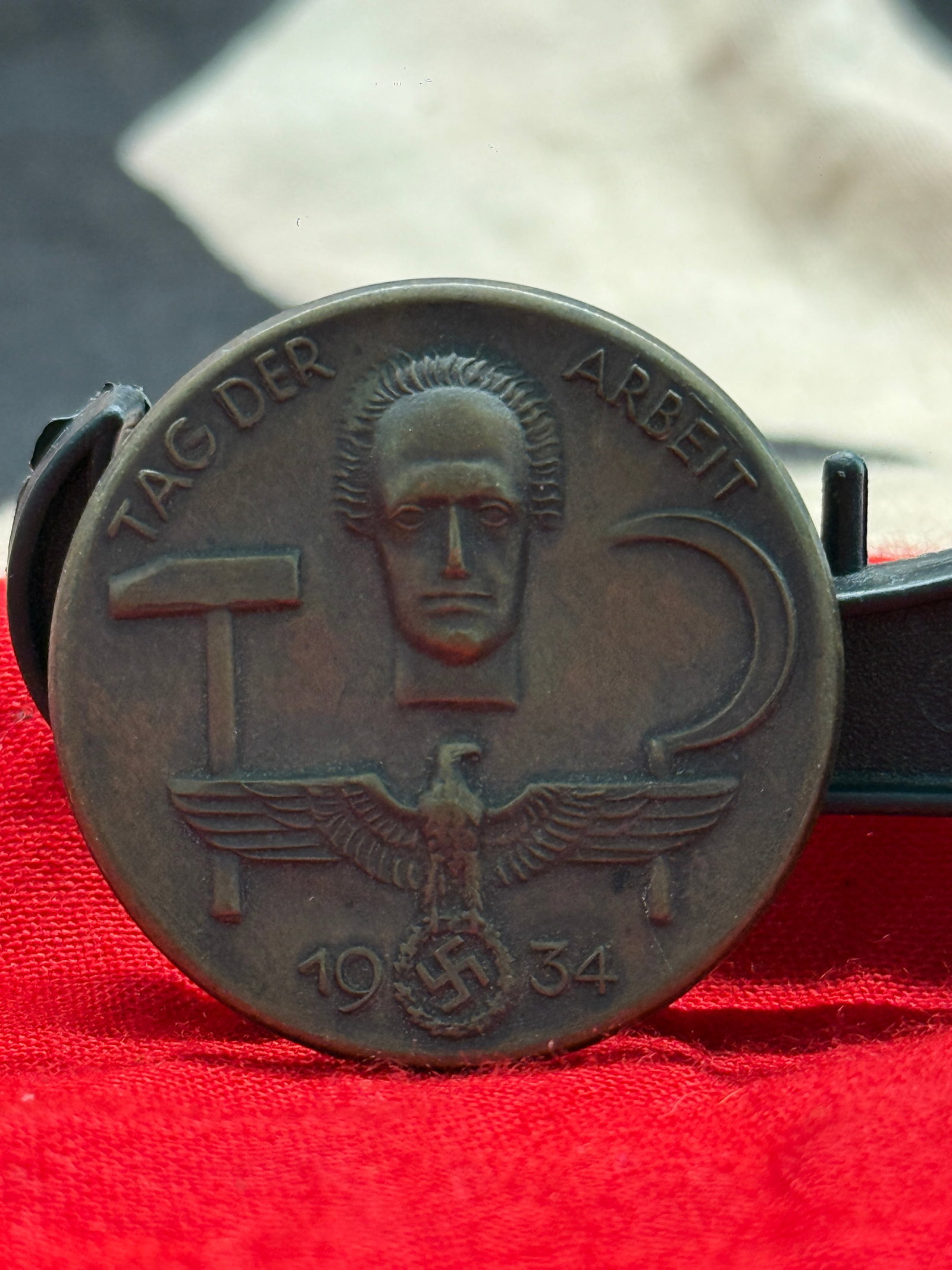 WWII German Reich Labor Service (RAD) "Tag der Arbeit 1934" Badge: This circular bronze-toned badge commemorates "Tag der Arbeit" (Day of Labor) 1934, featuring a portrait above the Reich eagle with wreath and swastika, alongside symbols representing labor including 