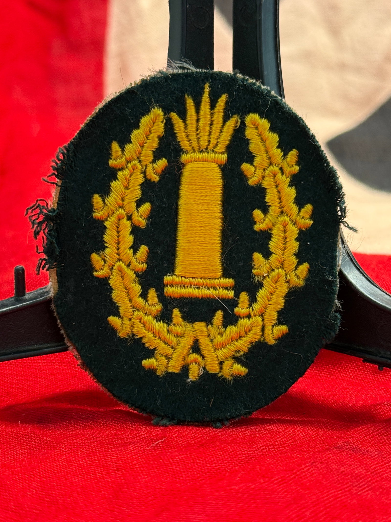 WWII German Kriegsmarine Coastal Artillery Sleeve Trade Badge: This embroidered Kriegsmarine sleeve insignia depicts a stylized coastal artillery gun barrel surrounded by an oak leaf wreath, executed in golden-yellow thread on a dark wool backing. Worn on the uni