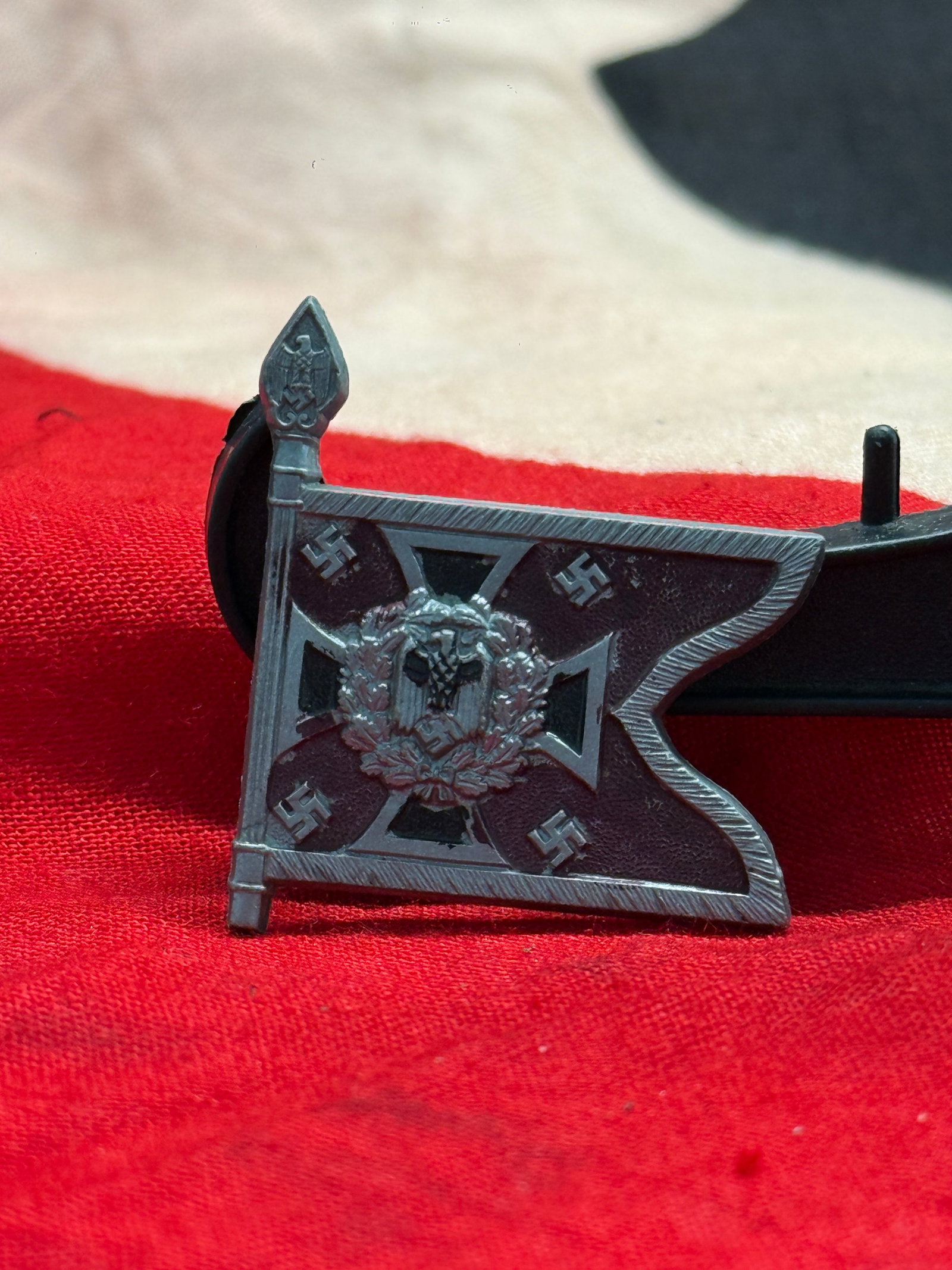 WWII German Nebeltruppe Flag Membership Badge: This die-struck metal badge is fashioned in the form of a military guidon bearing the Iron Cross, national eagle, and four swastikas, with the reverse stamped "Nebeltruppe" and "D.R.G.M." The Nebeltru